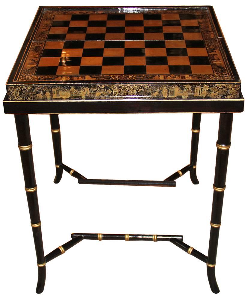 A 19th century English Import chinoiserie black lacquer games or cocktail table with later gate leg stand, that when closed creates a 10 1/2" deep profile, the foldable game board with chinoiserie detailing throughout, the board has one side