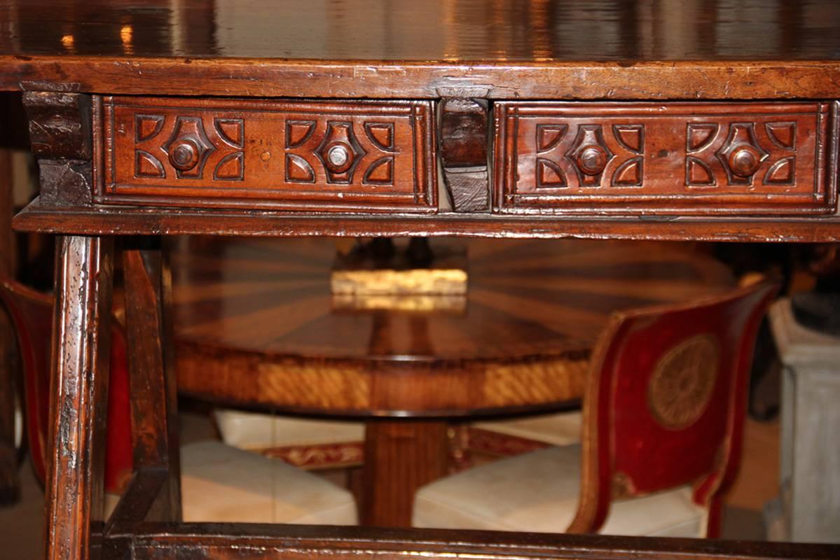 A fine Spanish walnut desk, the rectangular top above three short carved drawers with wooden knobs raised on plain legs joined by an H-stretcher.