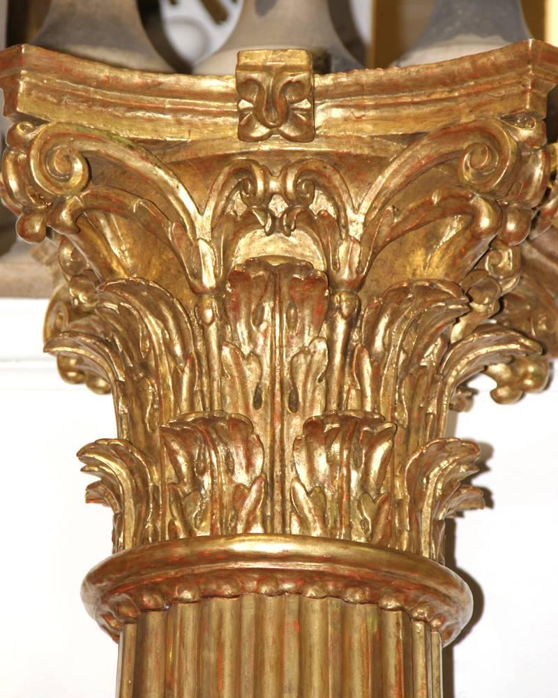 A pair of palazzo scaled 18th century Italian giltwood fluted columns, in 18-karat gold leaf and each topped with a Corinthian capital.