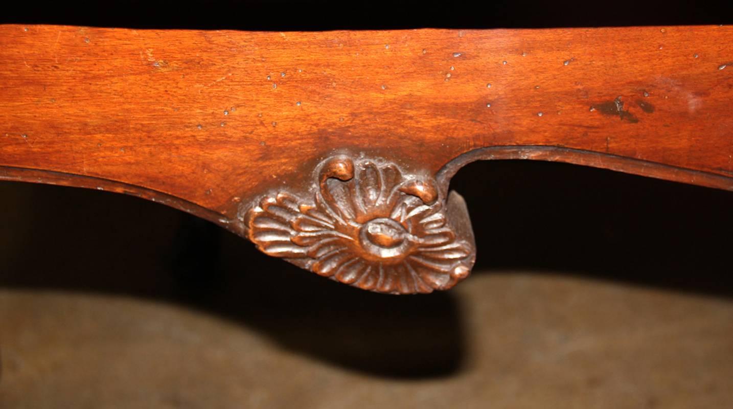 An extraordinary pair of Palazzo-Scaled early 17th century florentine walnut console tables, the shaped tops above conforming and notched aprons accented with carved florets and acanthus leaves and raised on cabriole legs terminating in slippered