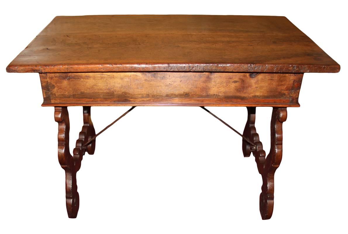 An 18th century Tuscan walnut desk, with two drawers and raised on shaped and fretted trestles connected by wrought iron stretchers.