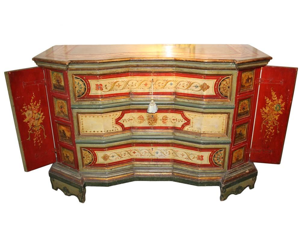 A Pristine 18th century Venetian polychrome concave block front commode credenza with three long drawers and two secret and canted side doors opening to reveal ten polychromed cubby drawers, embellished with mascaron, strings of pearls and foliate