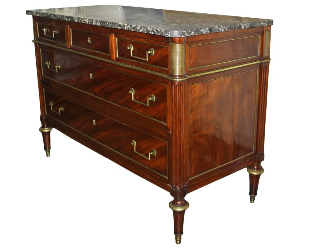 An 18th century Russian or French Louis XVI brass-mounted mahogany commode, the rectangular white-veined grey marble top with round outset corners above three graduated paneled drawers, the top drawer fronted as three drawers and accordingly