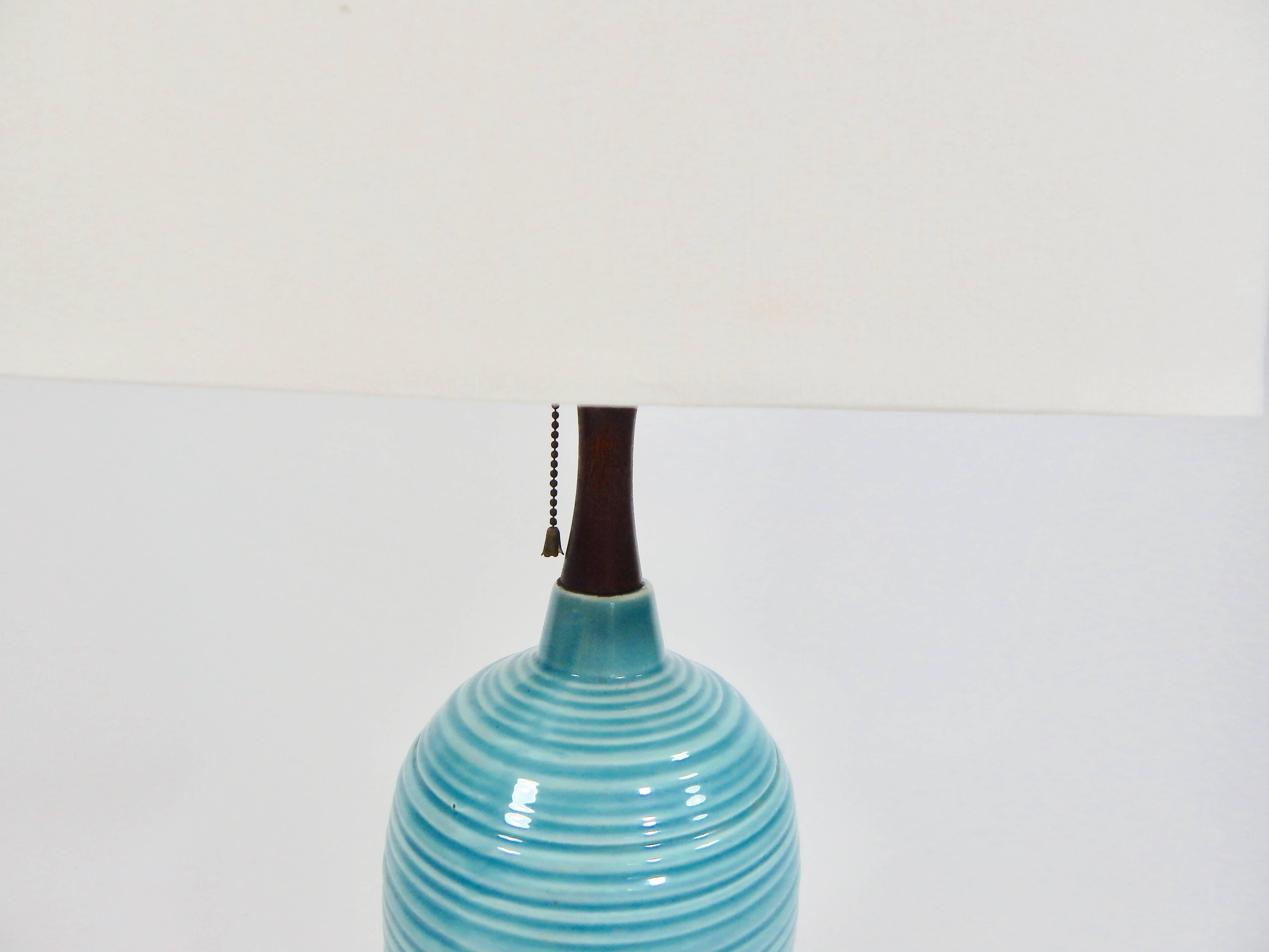 Mid Century 1960s ceramic turquoise table lamp. Walnut stem and metal pull switch. Brass hardware. Very good Original condition. 

Shade is for photo purposes only and is not included.

Measures: Lamp height is 30.5