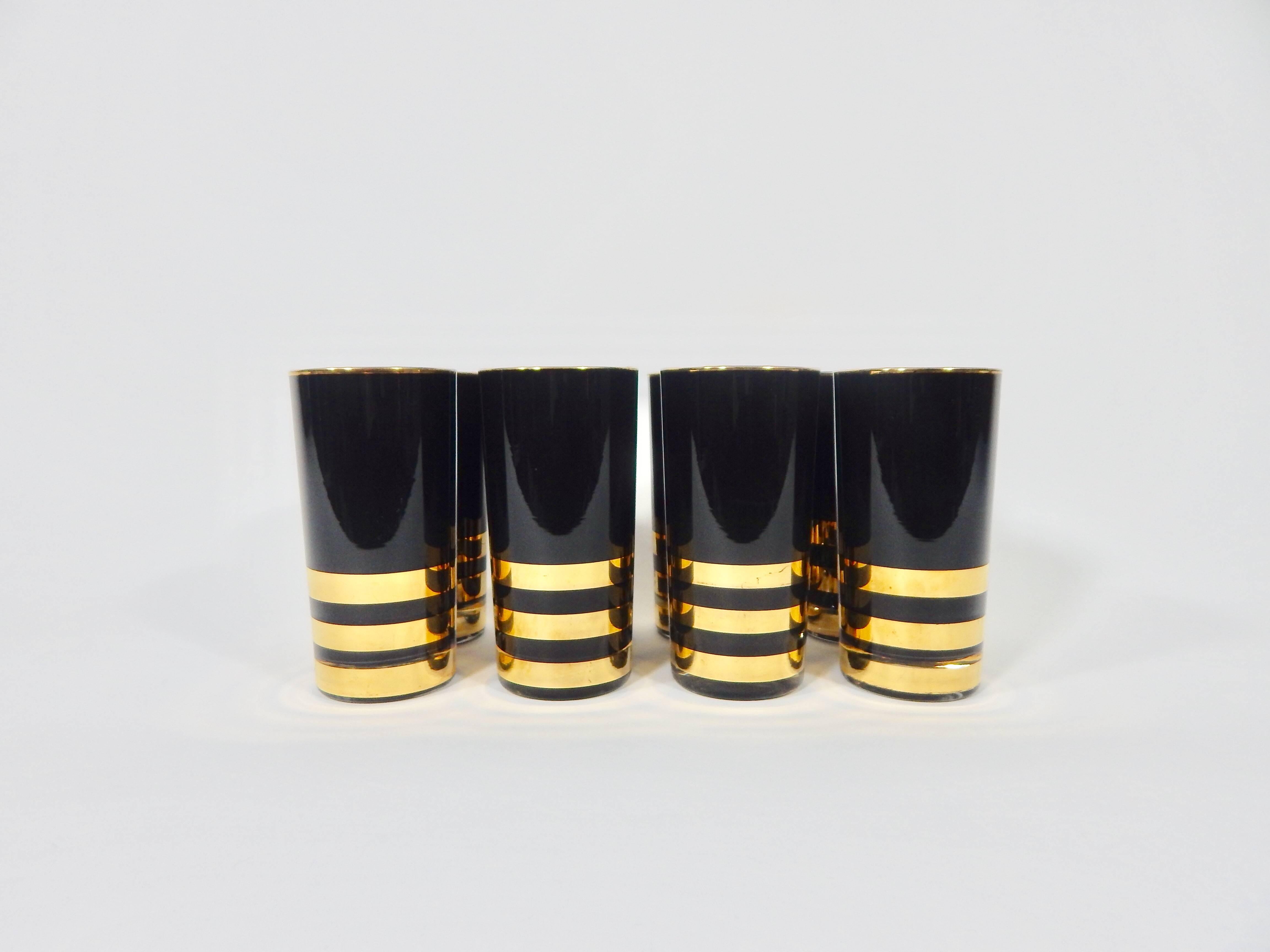 Midcentury late 1950s-early 1960s dramatic and glamourous glass set. Gold rimmed with gold stripes on black. Hollywood Regency. Perfect addition to a bar or table setting.