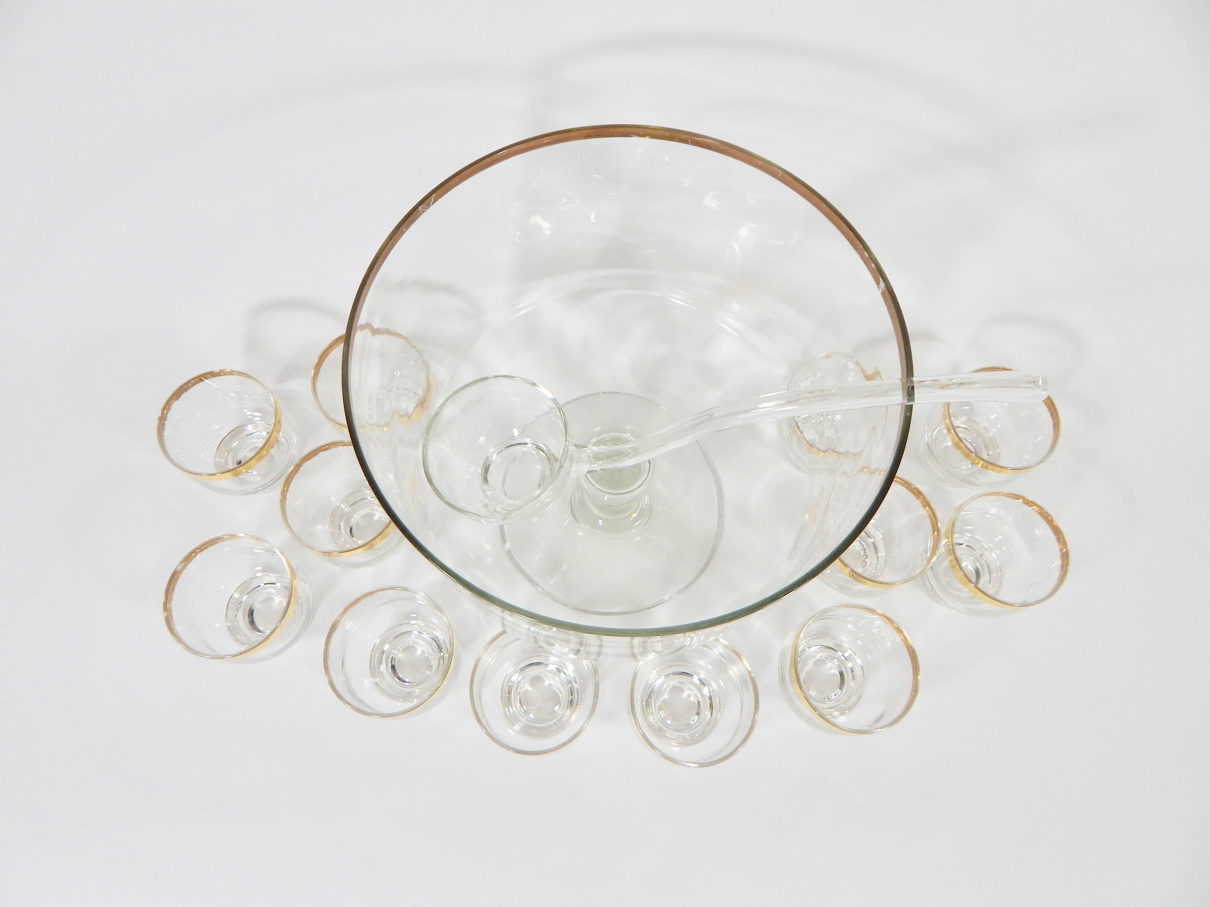 1960s glass punch bowl with gold rim. 12 matching glasses and ladle. This set was featured on Pinterests 56 best punch bowls. Glass in excellent condition. Gold exhibits some wear consistent with age see photos.

Measurement in inches:
Punch bowl -
