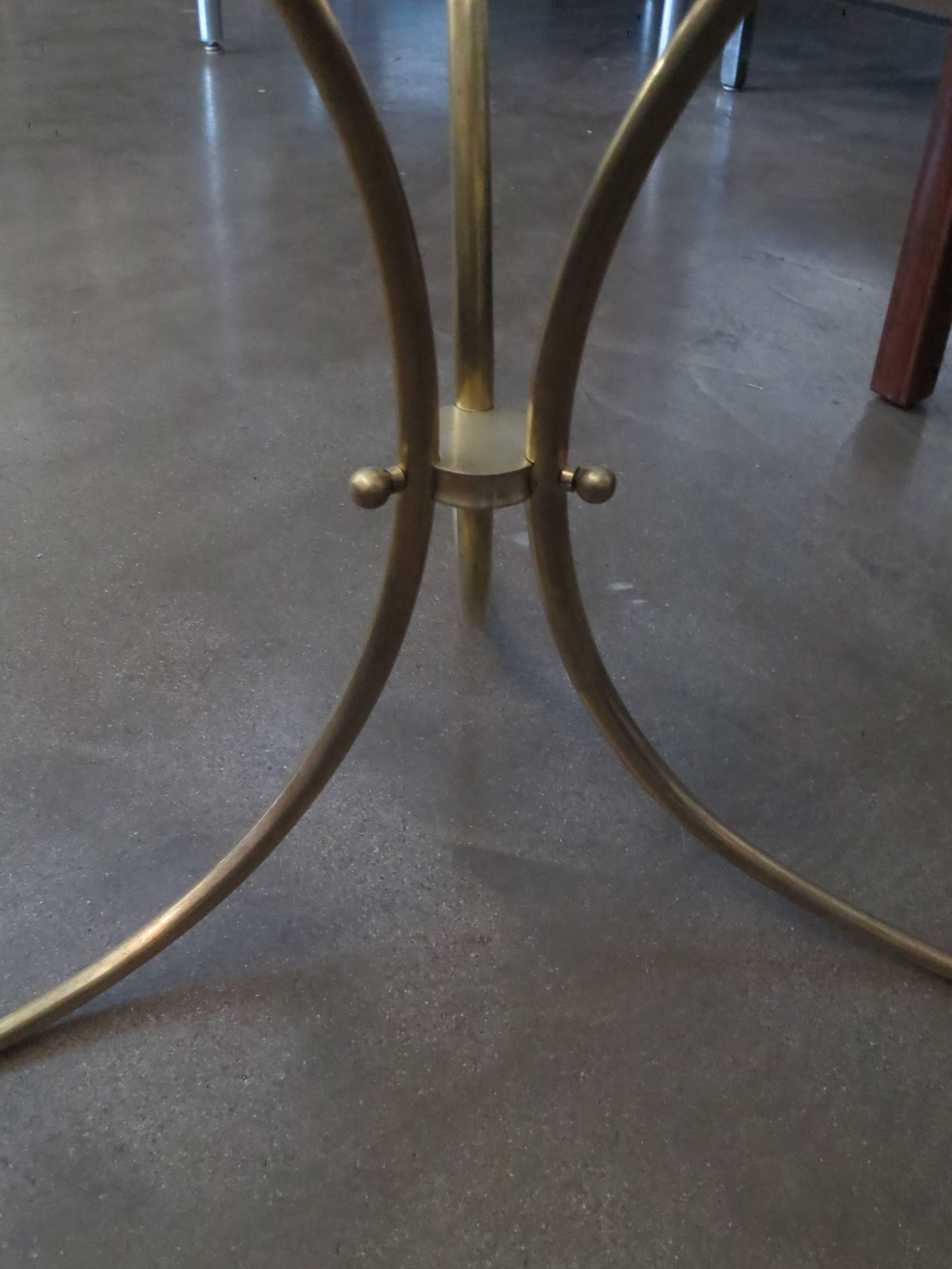 Sophisticated brass and glass table. The curving legs affix with elegant brass orbs to a center ring. The legs taper to a slender foot. A beautifully detailed side table.