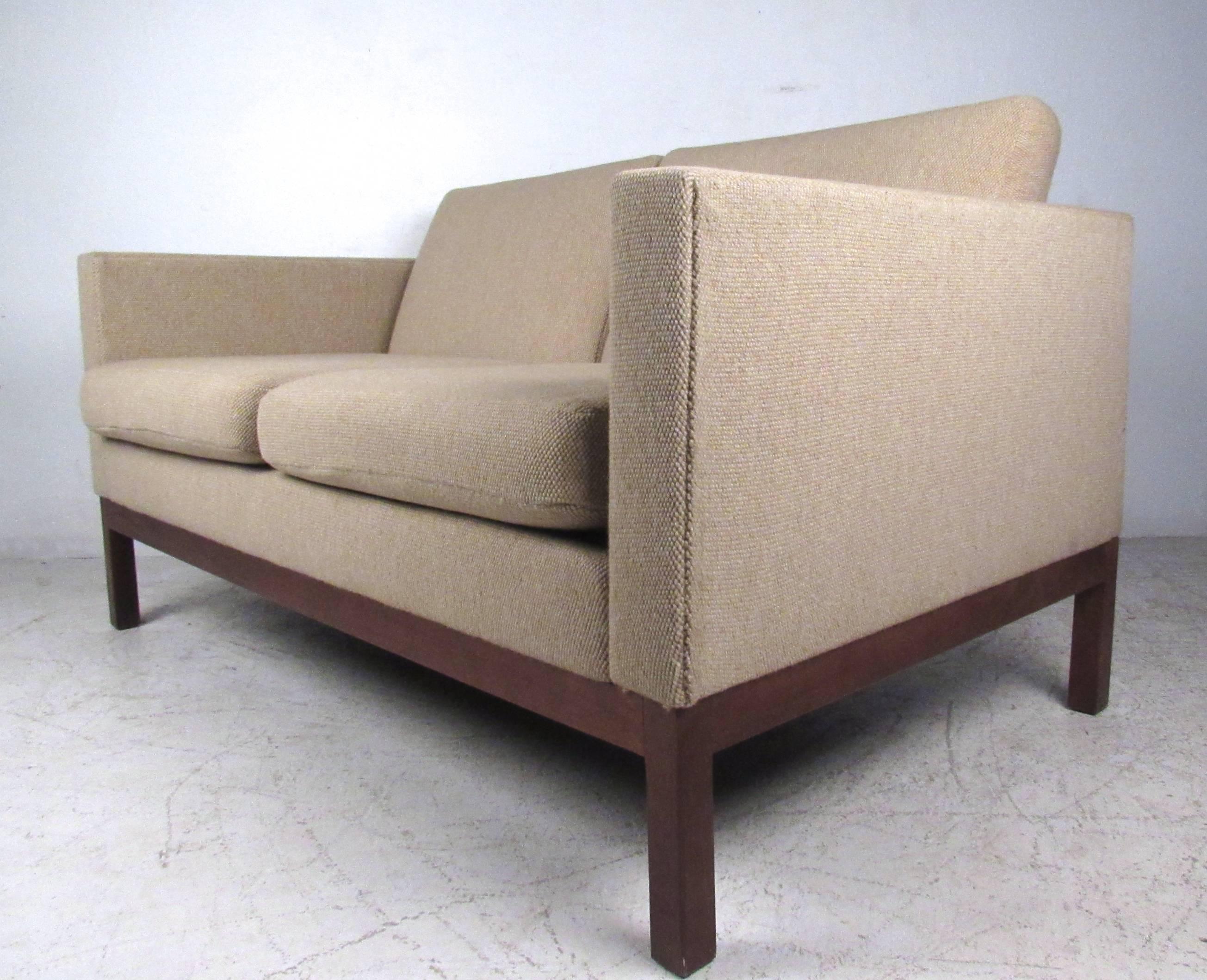This petite vintage love seat makes a comfortable two person seating addition to any interior. Sleek design with overstuffed removable cushions and sturdy walnut legs. Quality American manufacturing, clean modern lines, and quality vintage fabric