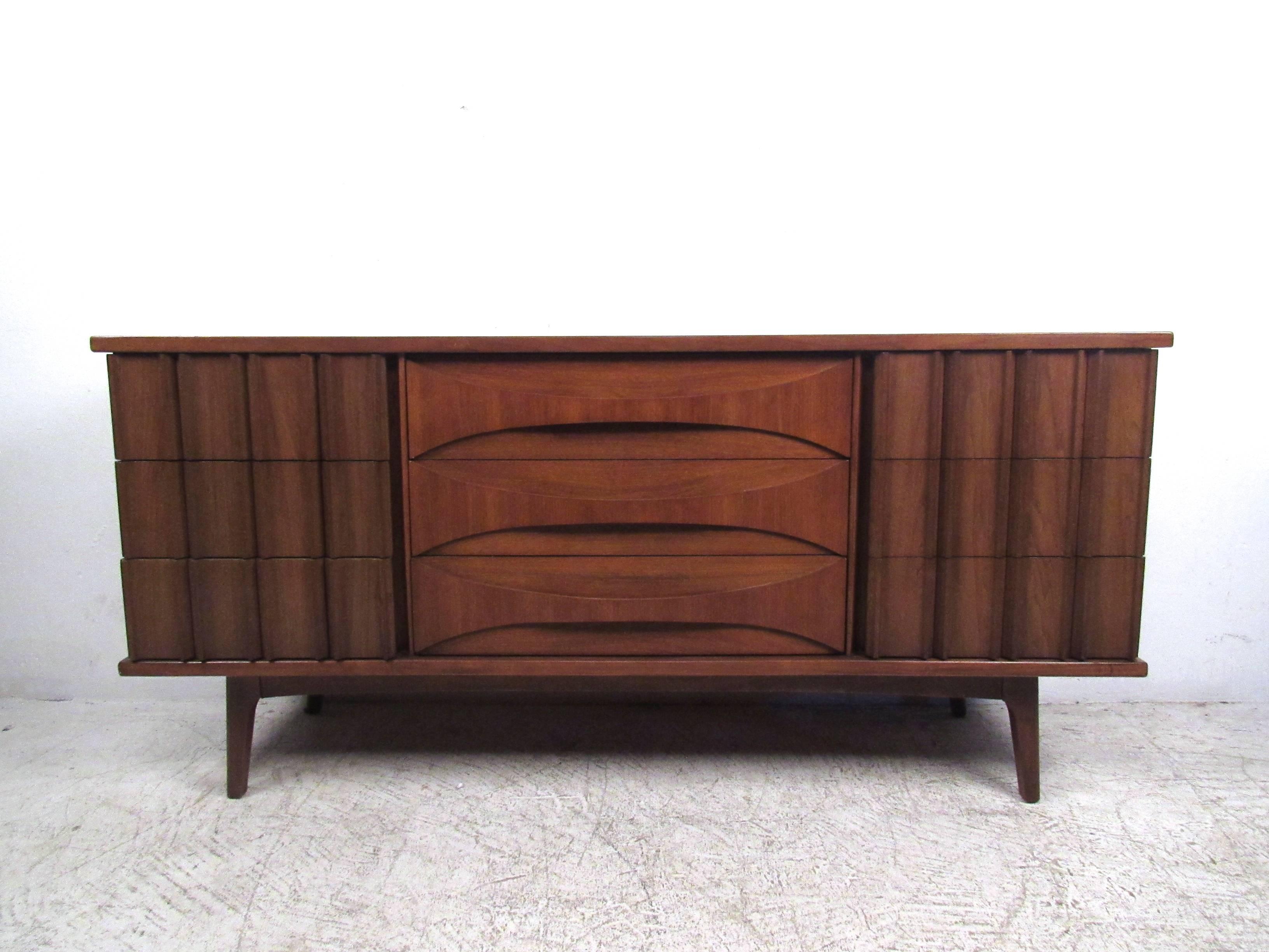 This three-piece matching bedroom set features unique Mid-Century walnut construction, including sculpted drawer fronts, tapered legs and plenty of stylish storage. Highboy Dimensions: 39 W 19.25 D, 45 H. Long Dresser: 64 W 18.5 31 H. Nightstand: 24