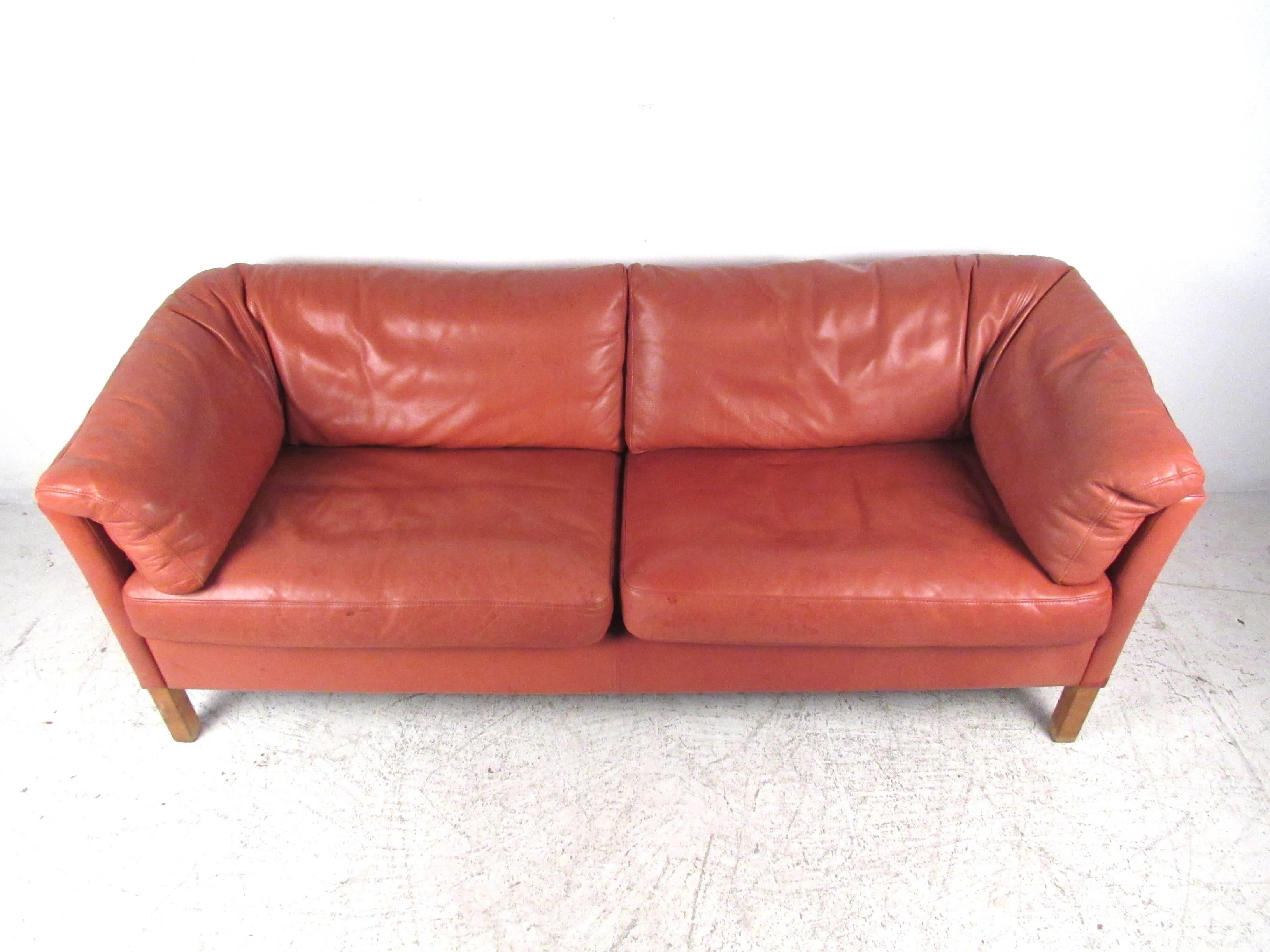 This beautiful pink leather love seat in the style of Borge Mogensen utilizes unique L-shaped back cushions for enhanced comfort and style. The versatile size of the piece makes this a great choice for an oversized love seat or a smaller sofa in a