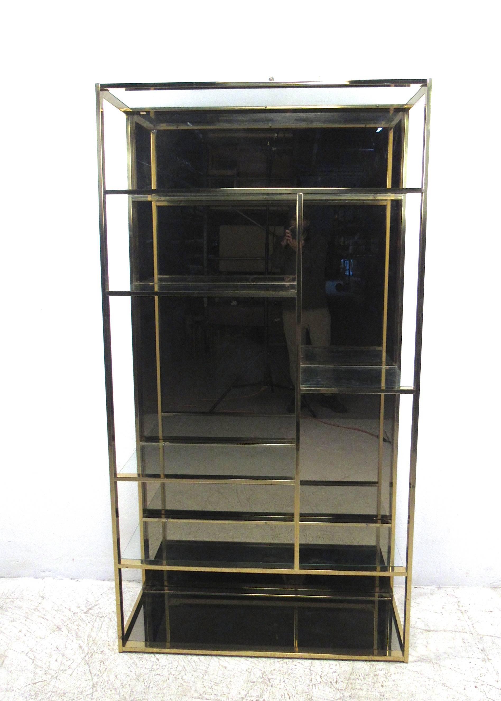 This unique brass finish etagere offers plenty of stylish storage or display space, complete with staggered size shelves for added variety. Unique smoked mirror background and bottom shelf add a nice vintage touch to the piece. Please confirm item