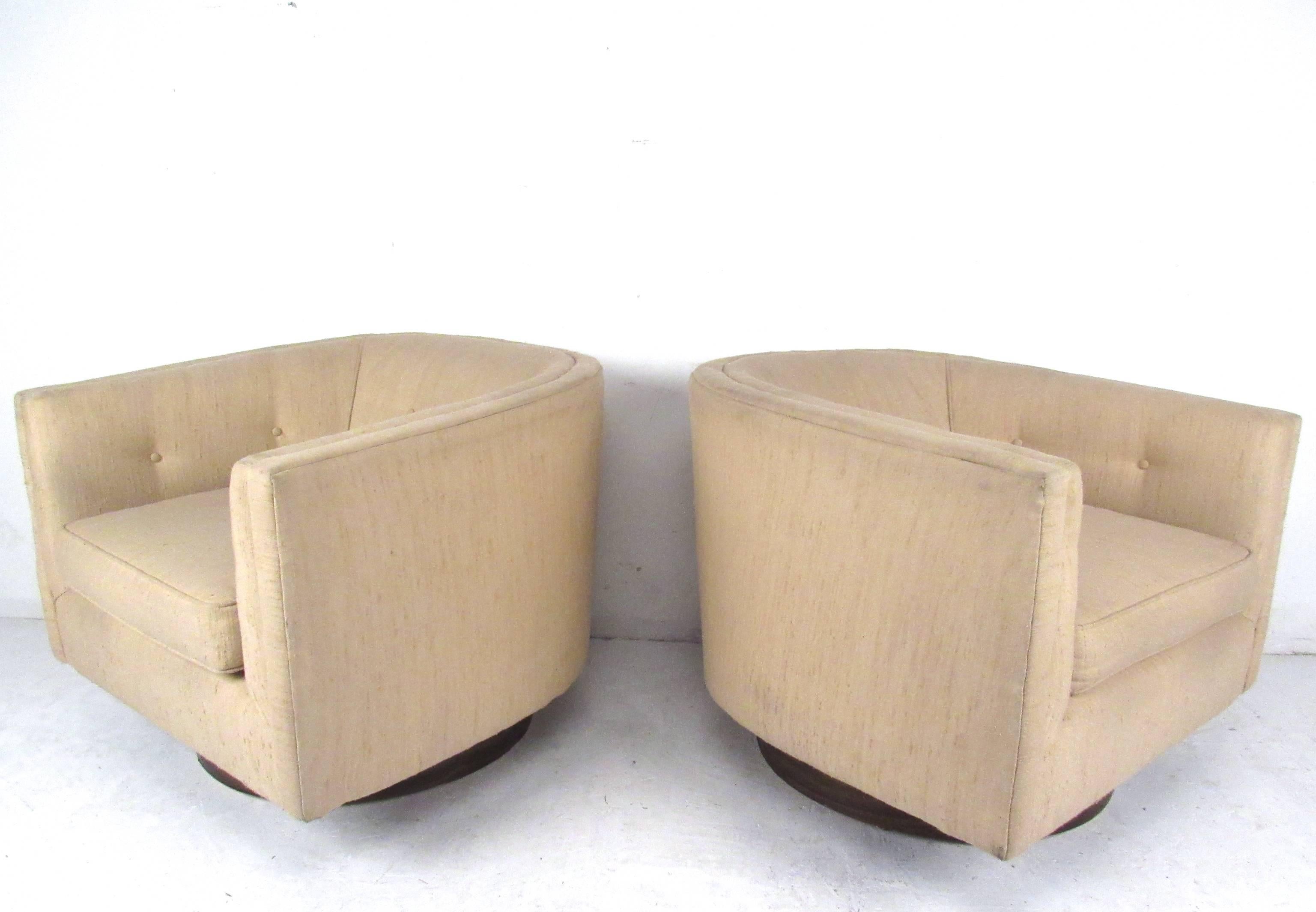 This pair of barrel back lounge chairs features tufted upholstery, walnut veneer base and 180 degree swivel function. Stylish Mid-Century design makes a unique and comfortable addition to any seating arrangement. Please confirm item location (NY or