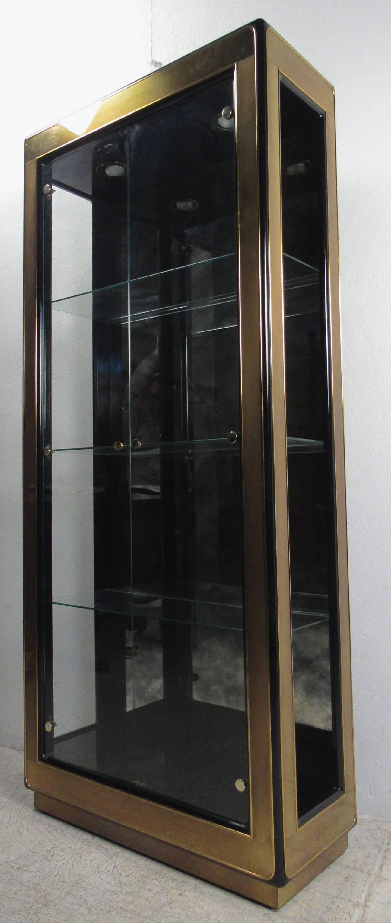 Vintage-modern display cabinet featuring glass shelving and brass trim, manufactured by Mastercraft. Stylish brass display cabinet makes a striking addition to home or shop display. Please confirm item location NY or NJ with dealer.