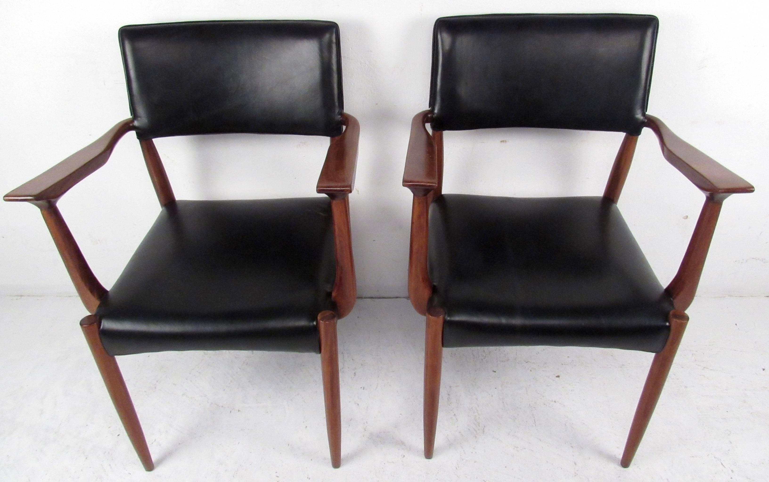 Two vintage-modern armchairs featuring sculpted rosewood body with leather upholstered seat and backrest.

Please confirm item location NY or NJ with dealer.