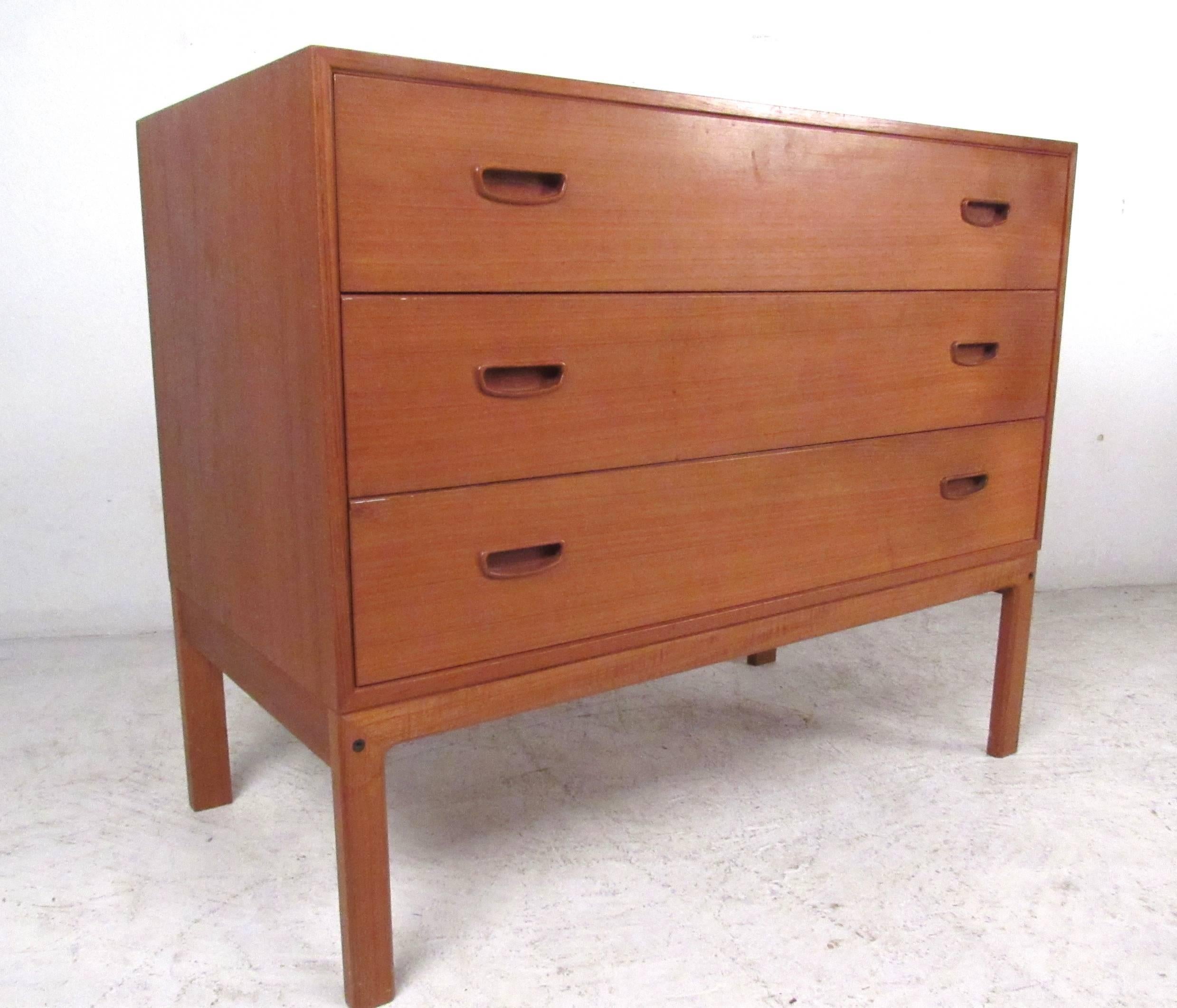 This teak finish dresser features carved drawer pulls, spacious bedroom storage, and a unique vintage feel. Danish manufacturers mark on the piece, makes a great addition to any interior. Please confirm item location (NY or NJ).
