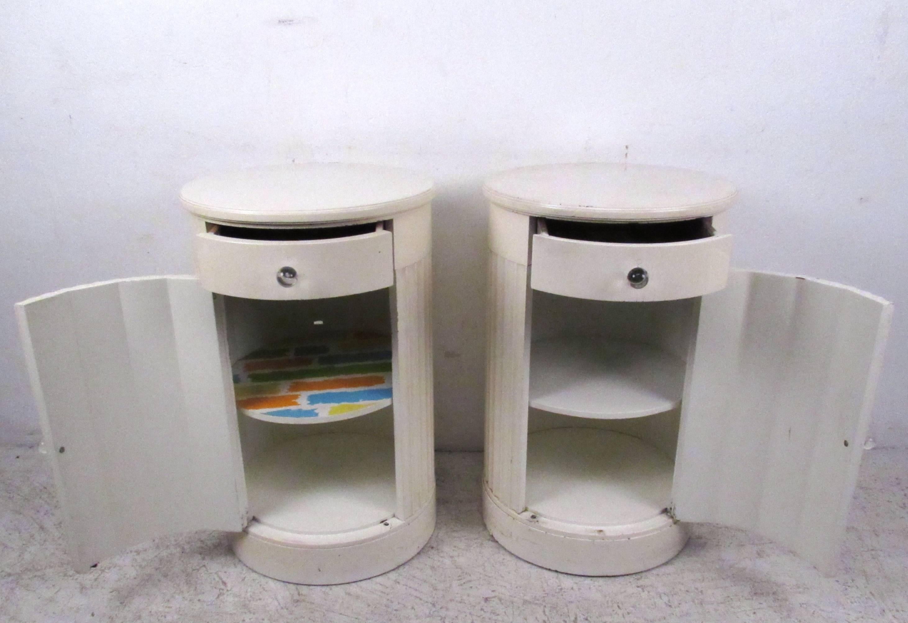 This unique vintage pair of column style end tables features scalloped painted doors with an extra drawer and shelves for plenty of storage. This stylish pair of John Stuart tables make a stylish addition to any room. Please confirm item location