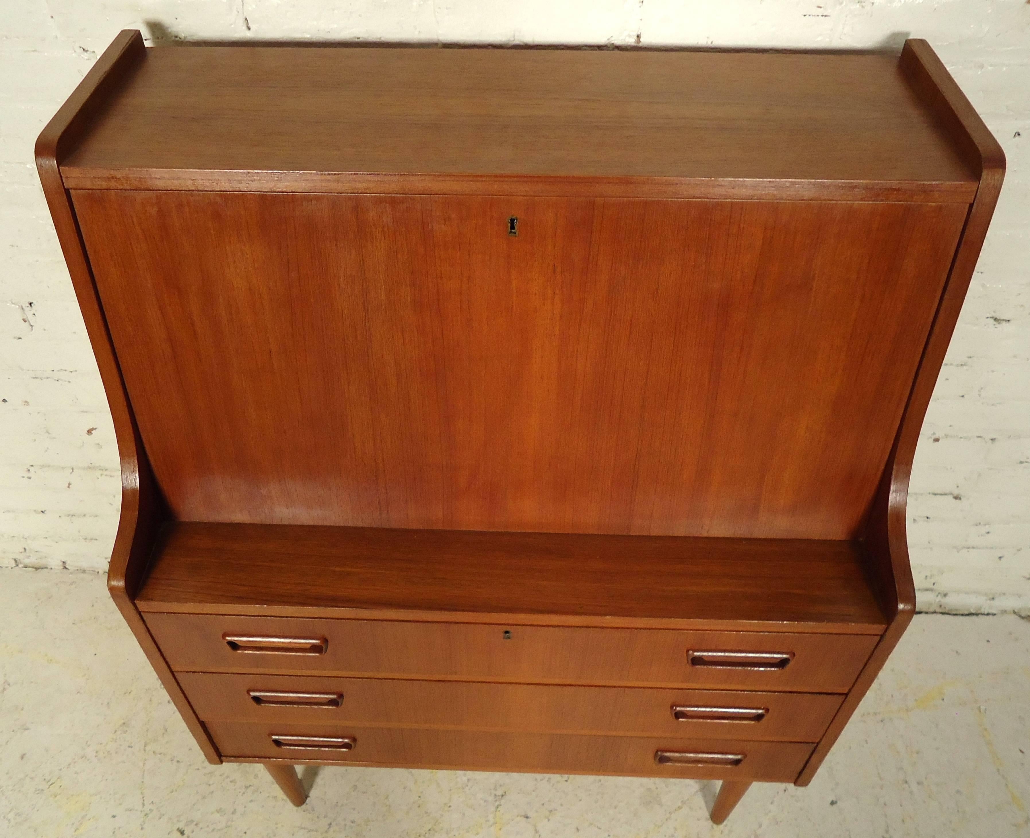 Vintage-modern secretary desk featuring three drawers with sculpted handles, drop front and beautiful teakwood grain.

Please confirm item location NY or NJ with dealer.