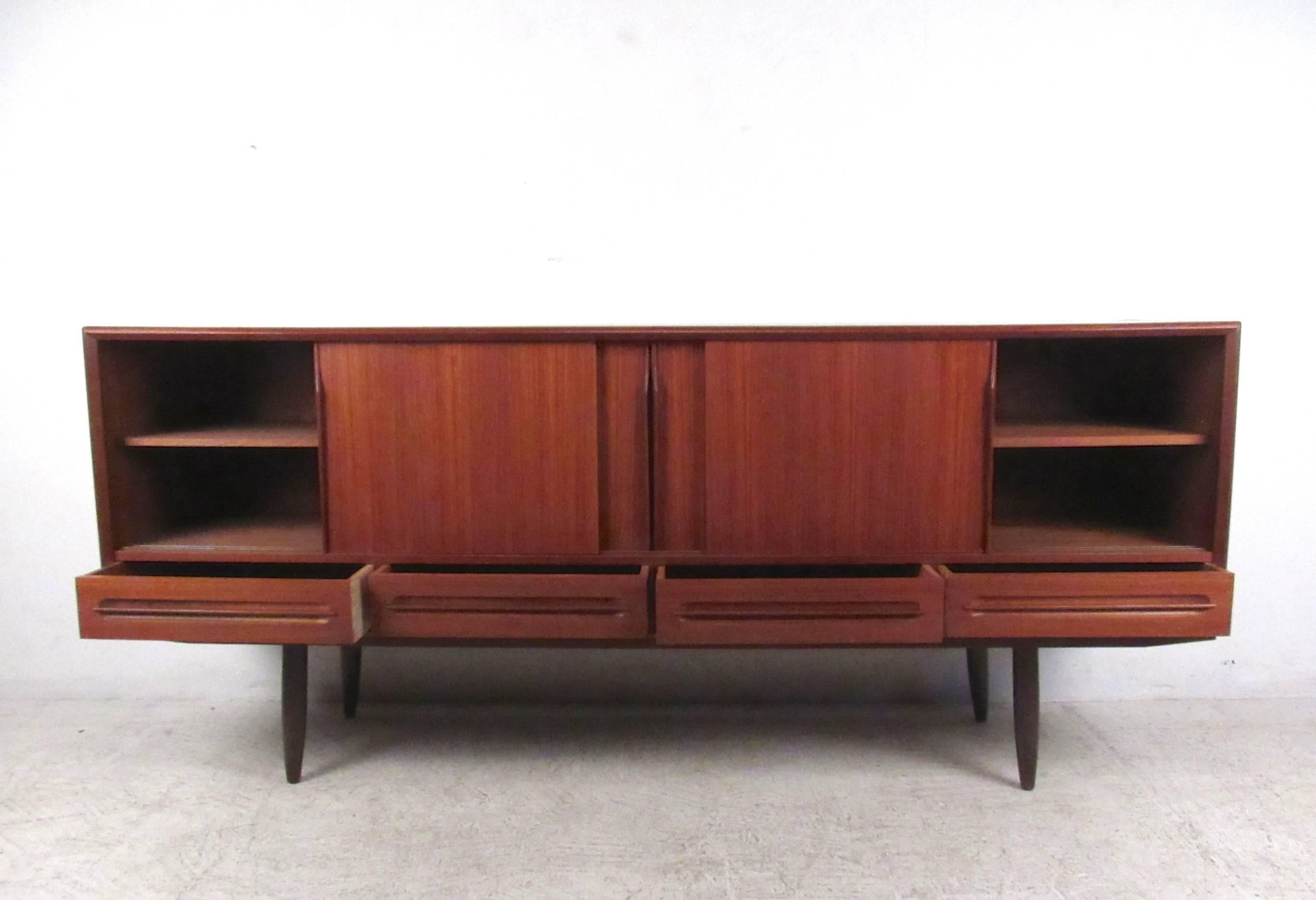 This stunning vintage teak sideboard makes a stylish storage piece in a variety of settings. Quality Teak veneer, unique carved pulls, interior rosewood drawers and plenty of cabinet storage add to the versatility of this Danish piece. Please
