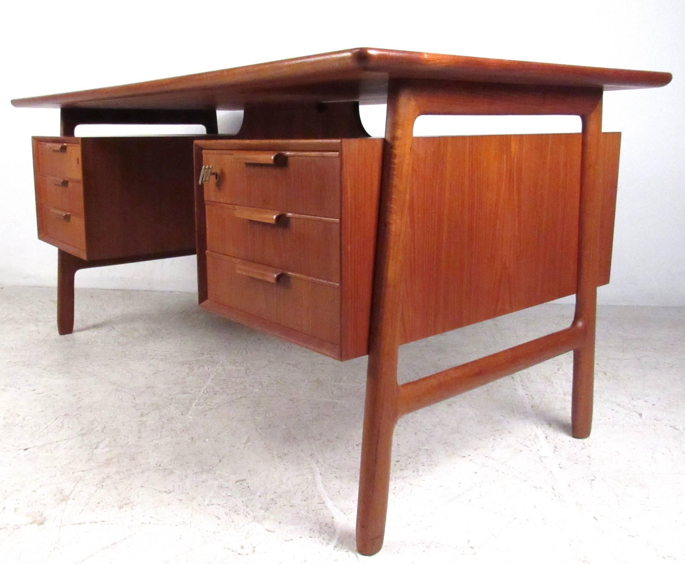 This beautiful vintage teak desk by Oman Junior features a beautiful double-sided design with plenty of storage for home or office. Sculpted frame with floating top workspace, this Mid-Century style desk refuses to sacrifice style for storage space.