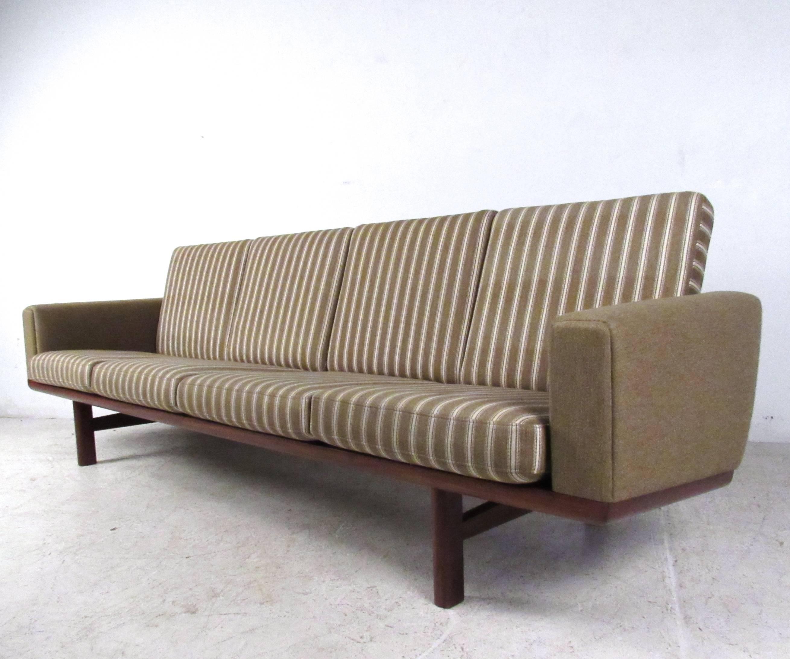 This beautiful vintage four seat sofa offers a stylish seating solution for a variety of interiors. Wegner's unique slat back design pairs wonderfully with the piece's straight lines, vintage fabric and spacious seats. Designed by Hans Wegner for