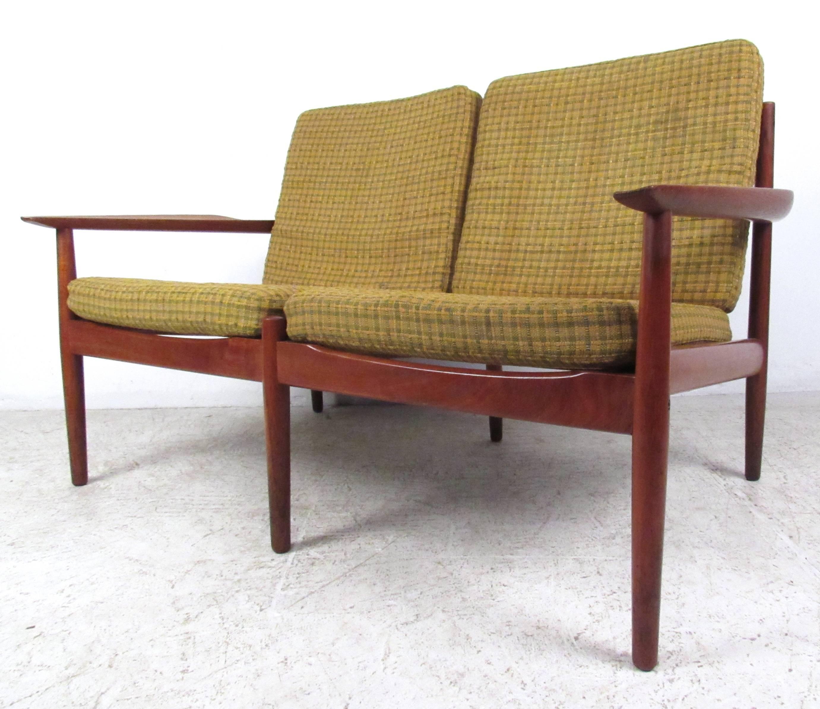 This Danish vintage two-seat offers a stylish teak finish with a uniquely sized two-seat settee. By Arne Vodder, this seating option is perfect for home or office setting. Please confirm item location (NY or NJ).