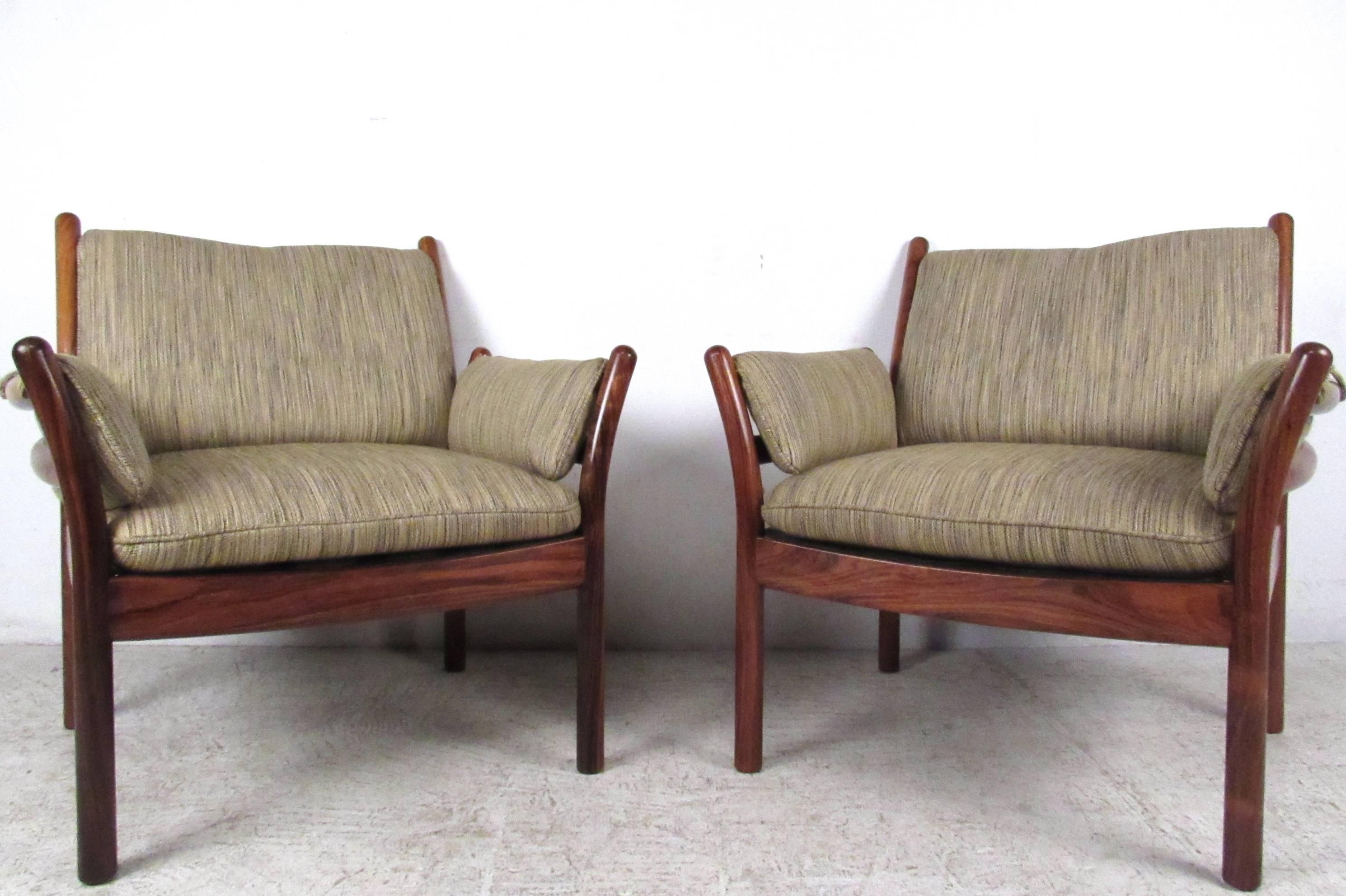 This beautiful matching pair of vintage rosewood armchairs features the unique Scandinavian Modern style of designer Illum Wikkelsø. The beautiful vintage fabric seat cushions are attached to its sleek and stylish hardwood frame. Please confirm item