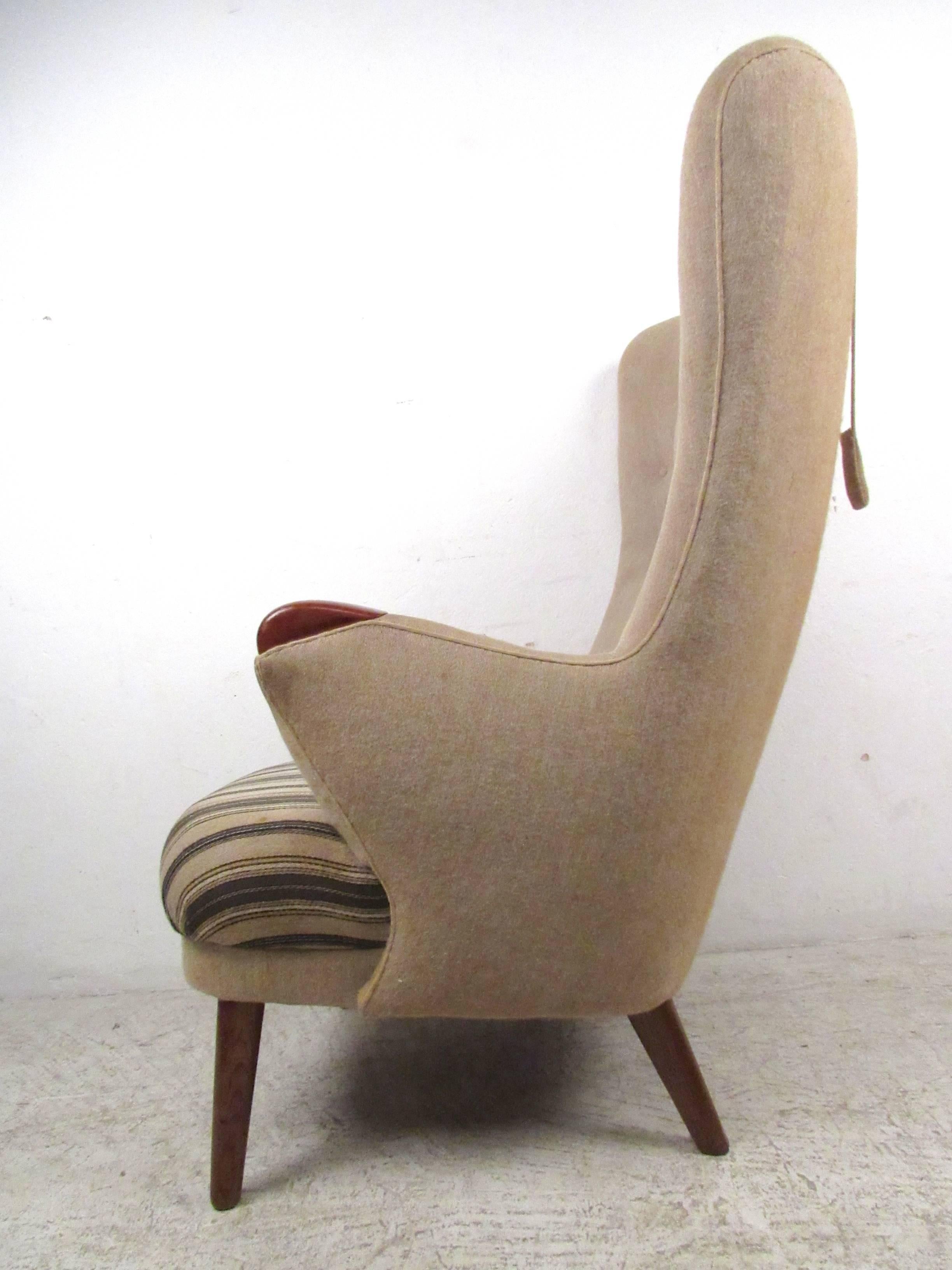 This unique vintage lounge chair features a unique tufted seat back, wooden armrests and tapered legs. The stylish shape of this mid-century chair is well accented with it's striped seat upholstery. Please confirm item location (NY or NJ).