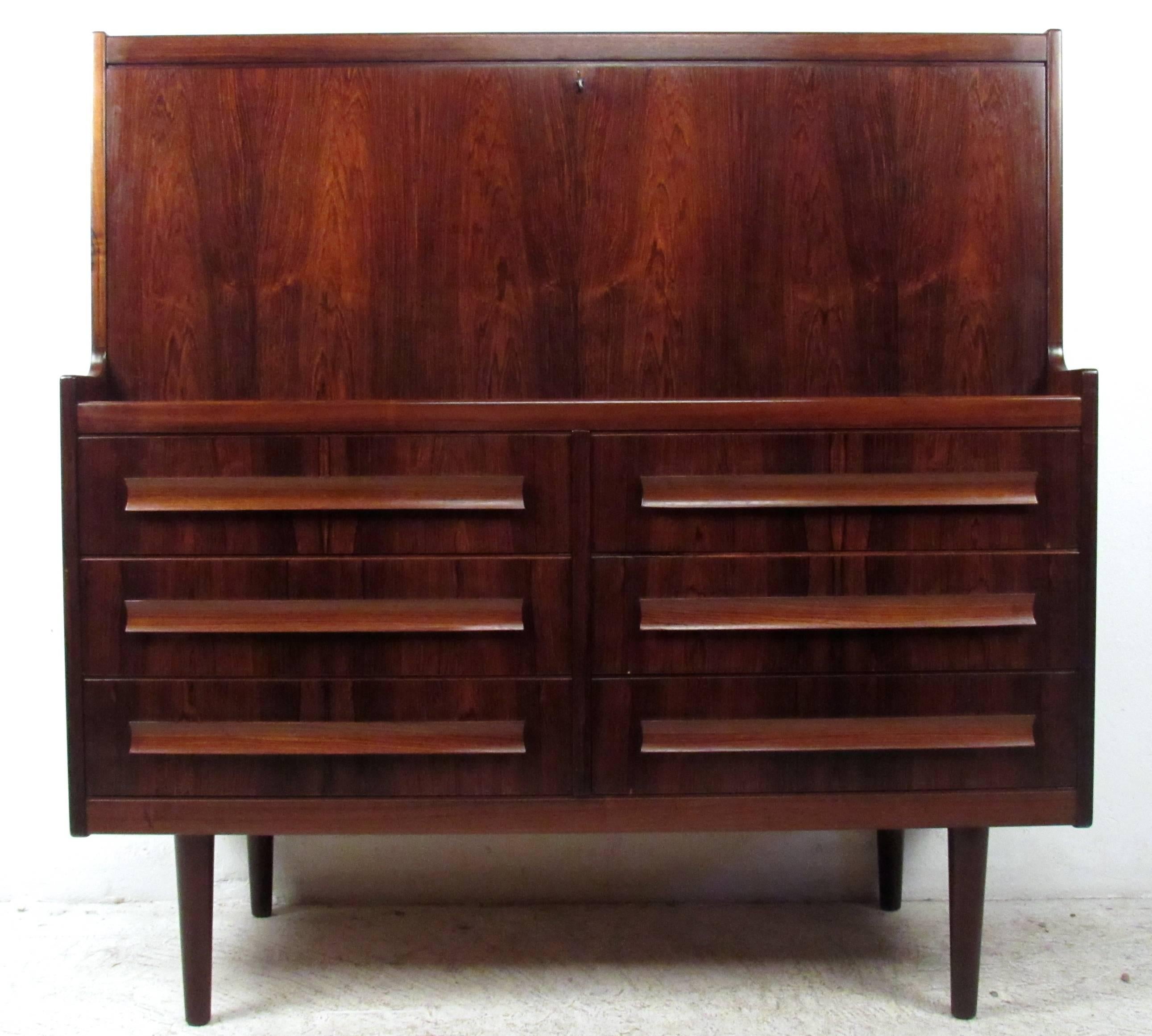 This beautiful vintage chatol features a rich rosewood finish, an optimal layout for organizational storage, and a spacious drop front work space. Unique drawer pulls, tapered legs, and a wide frame add to the design of the piece. Please confirm