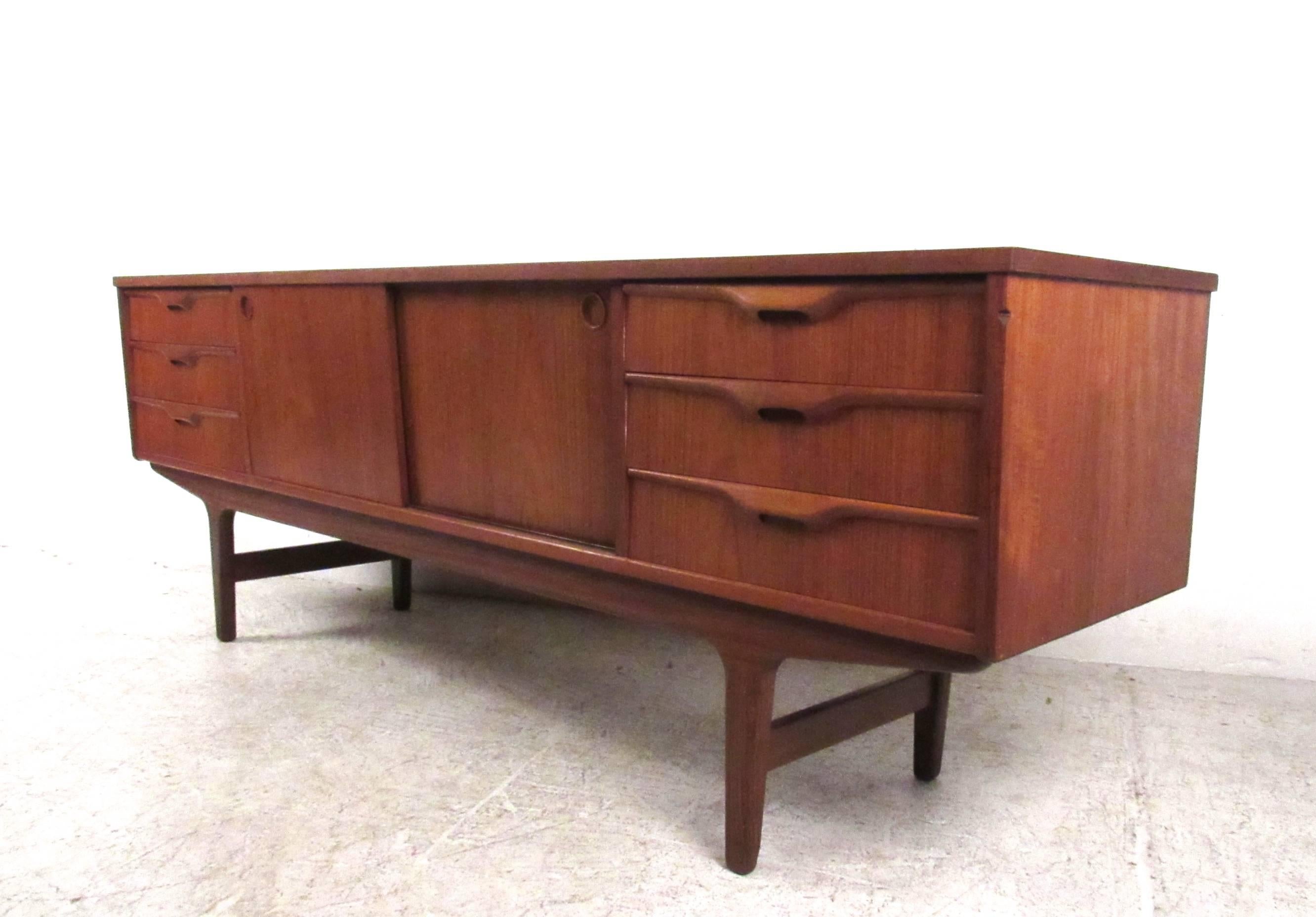 This uniquely sized vintage sideboard features a combination of six storage drawers and sliding cabinet doors. Quality Scandinavian Modern construction, carved handles, and its petite size add to the charm of the piece. Ideal storage credenza for