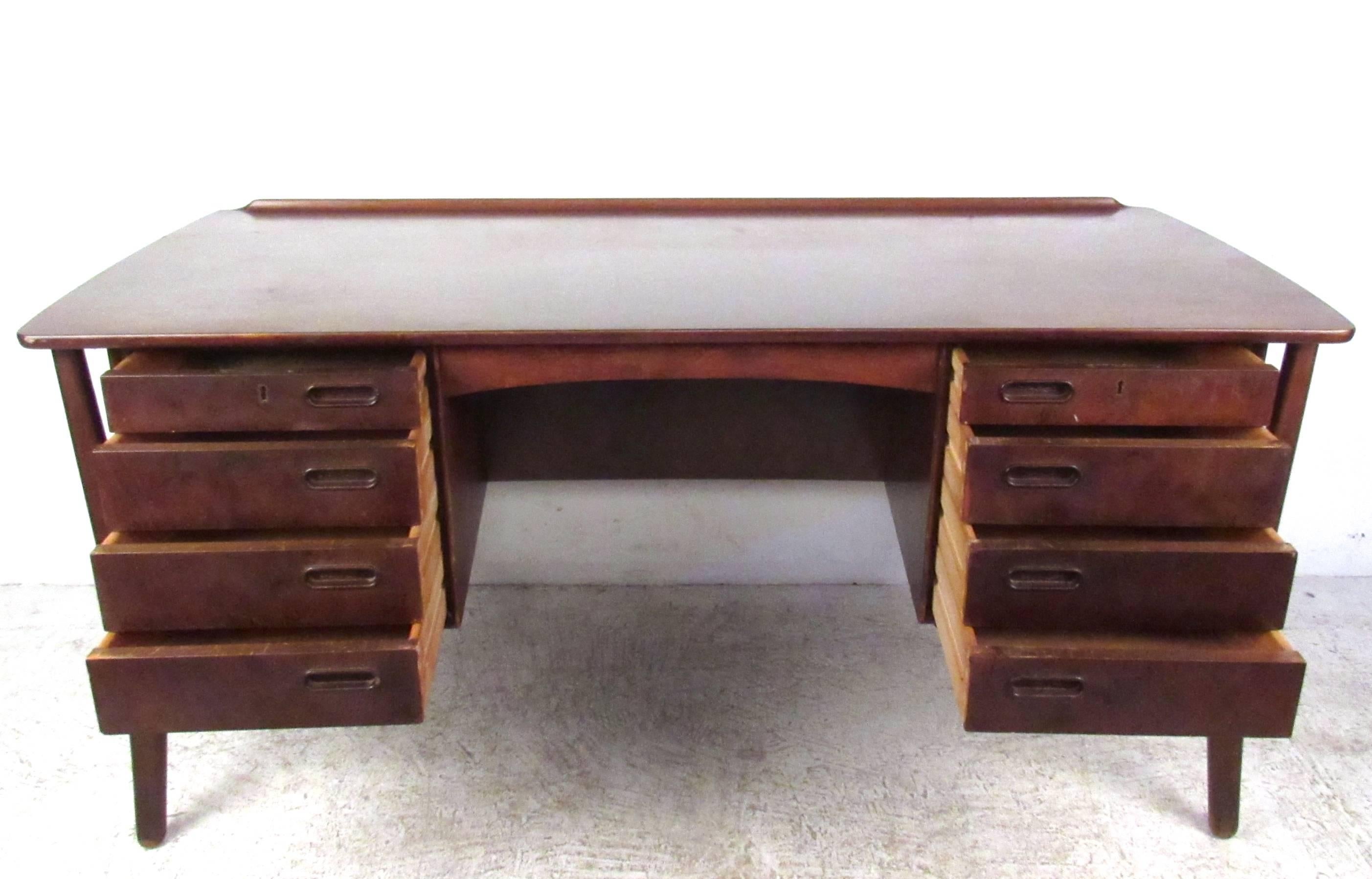 This stylish vintage desk by Svend Aage Madsen features a unique floating frame design with wonderful sculpted legs. Eight drawers and an addition cabinet/shelf space on the back side of the piece compliment the spacious desktop work area with