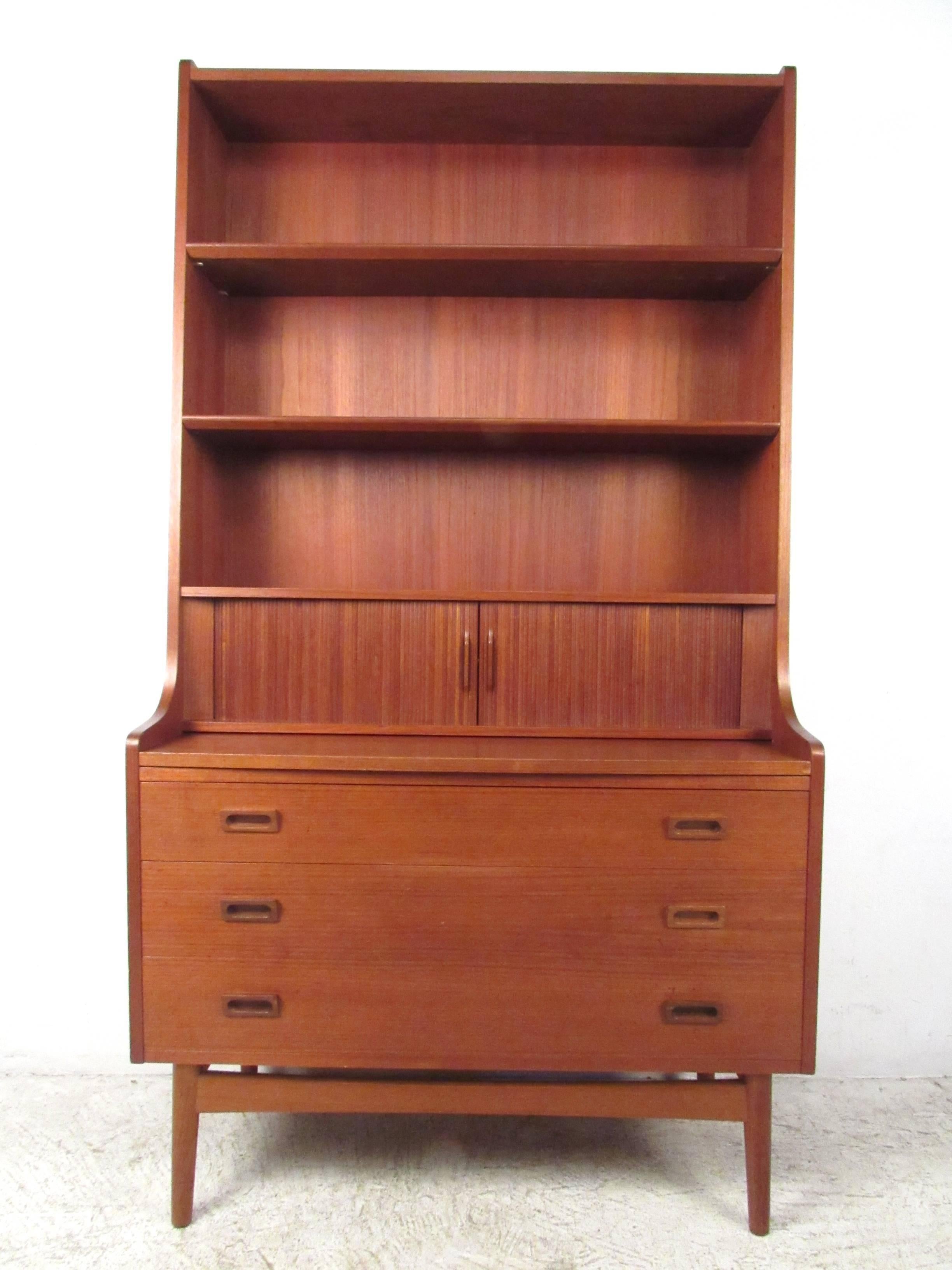 This mid-century modern Danish teak bookshelf features plenty of display space and storage. Pull-out work surface makes this Borge Mogensen style secretary desk a versatile piece for smaller rooms, without sacrificing organizational options or