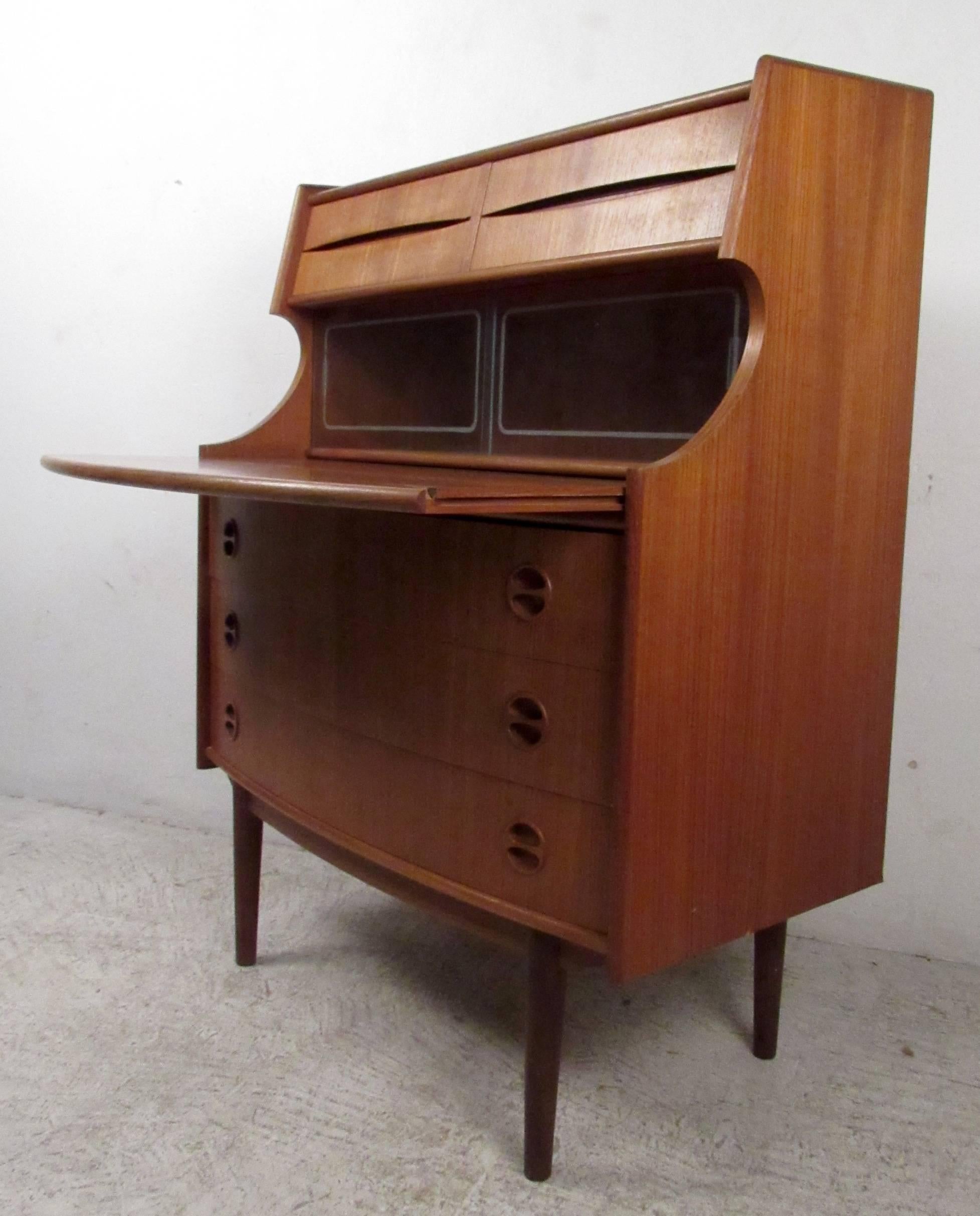 Vintage modern teak secretary featuring uniquely sculpted body with ample drawer and cabinet space including two sliding glass doors on front with pull-out writing desktop. Designed by Arne Vodder for Sibast Mobler.

Please confirm item location NY