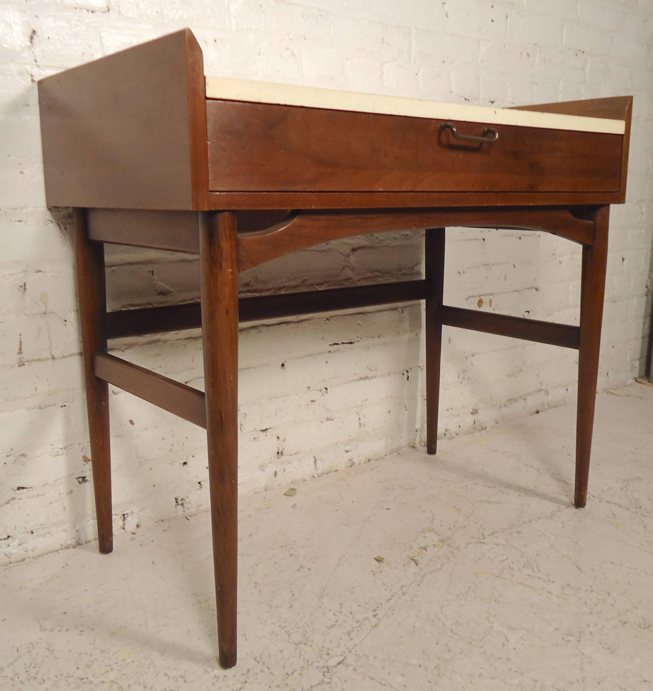 Mid-Century desk by American of Martinsville. Features white top, walnut frame, raised sides and tapered legs. Single drawer. Work well as an attractive entryway table.

(Please confirm item location - NY or NJ - with dealer).
 