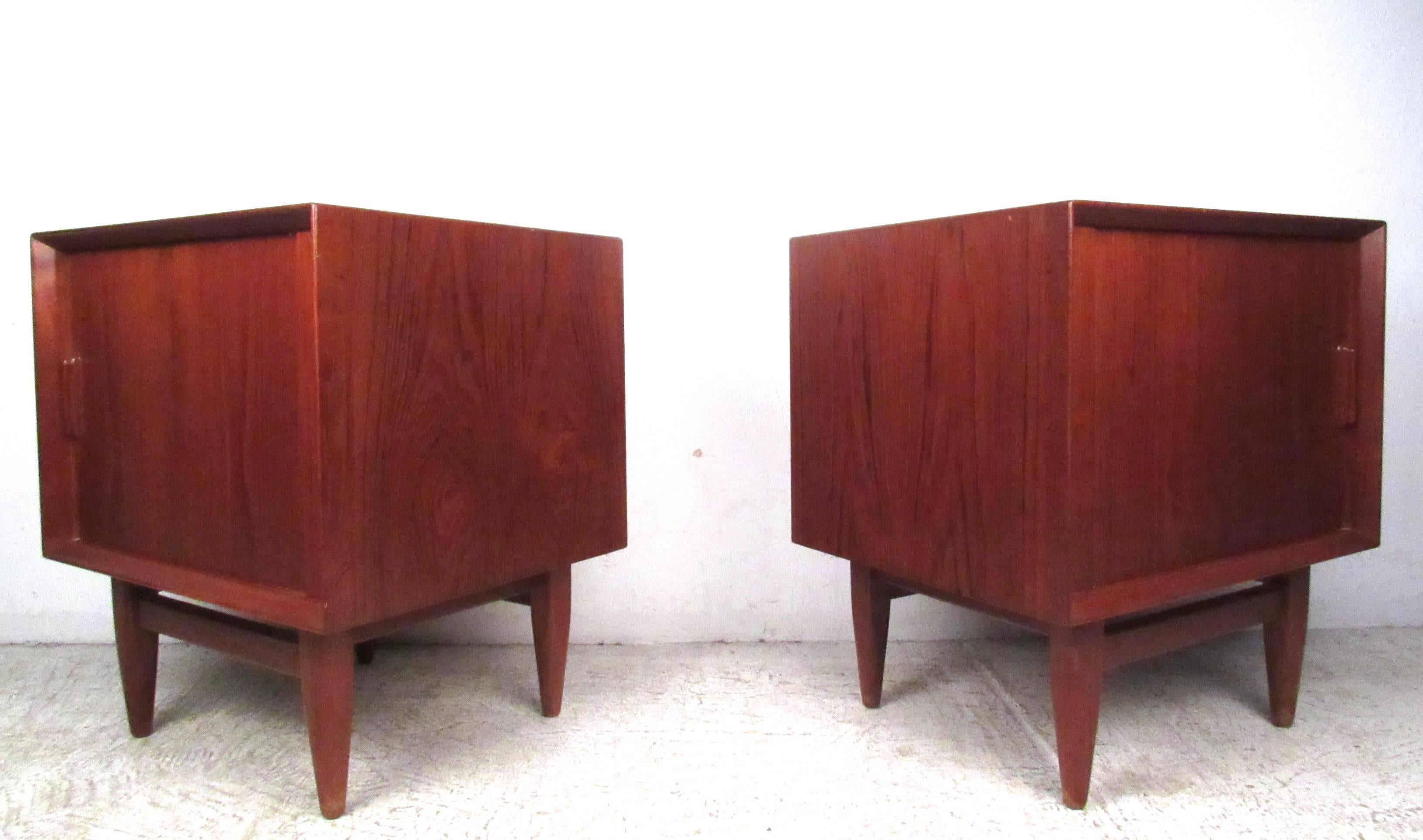 This pair of vintage Danish teak nightstands offers a great option for any interior, featuring tapered legs, tambour doors, and finished backs. Open cabinet space with top drawer make organization easy. Please confirm item location (NY or NJ).
