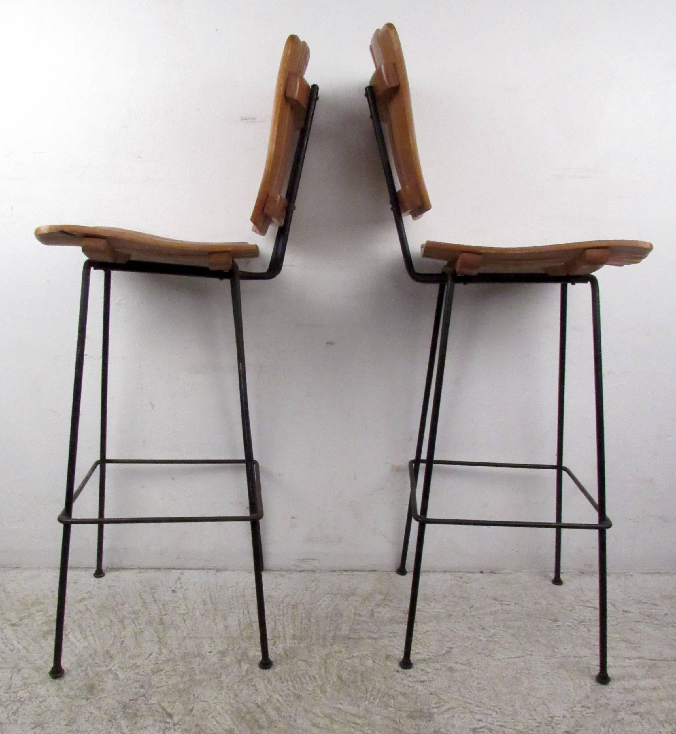 Two vintage-modern stools featuring iron bases and slat wood seat and back, designed by Arthur Umanoff.

Please confirm item location NY or NJ with dealer.