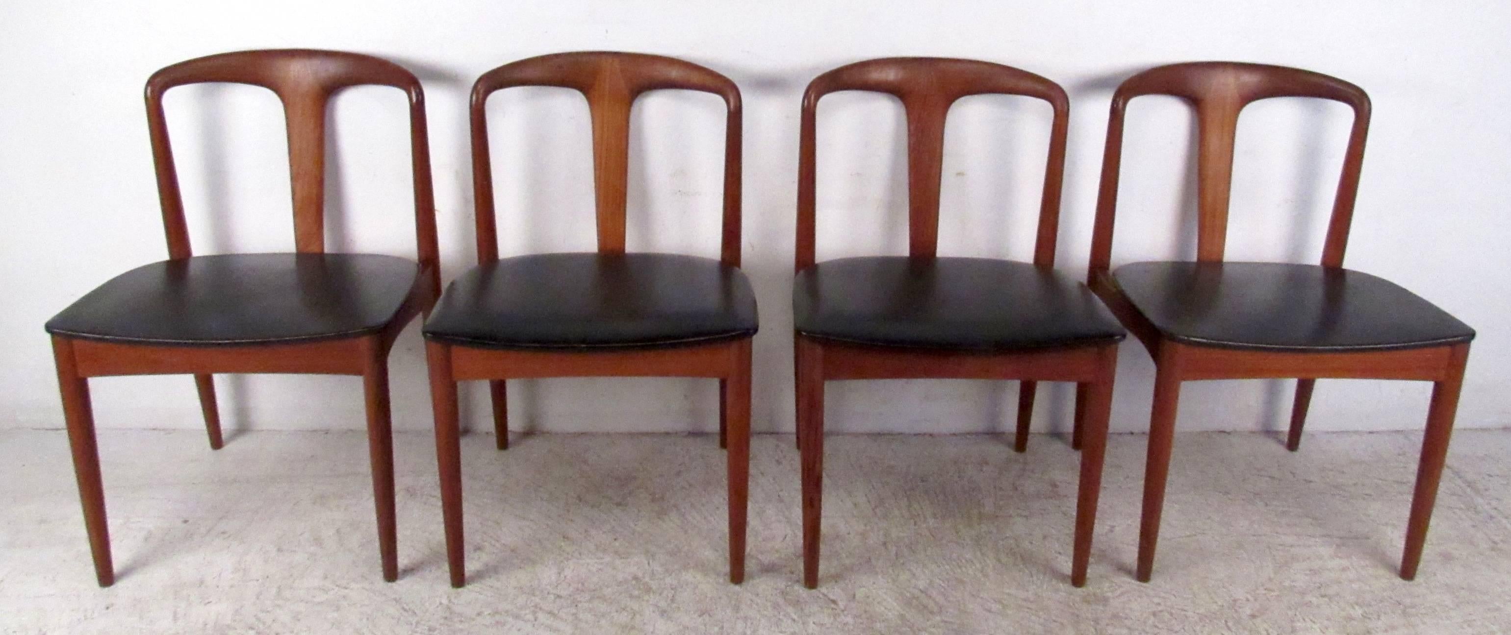 Set of vintage modern teak dining chairs manufactured in Denmark by Vamo Sonderborg. A unique design that boasts arched backrests with a single slat in the center and tapered legs. A thick padded seat covered in black vinyl ensures maximum comfort