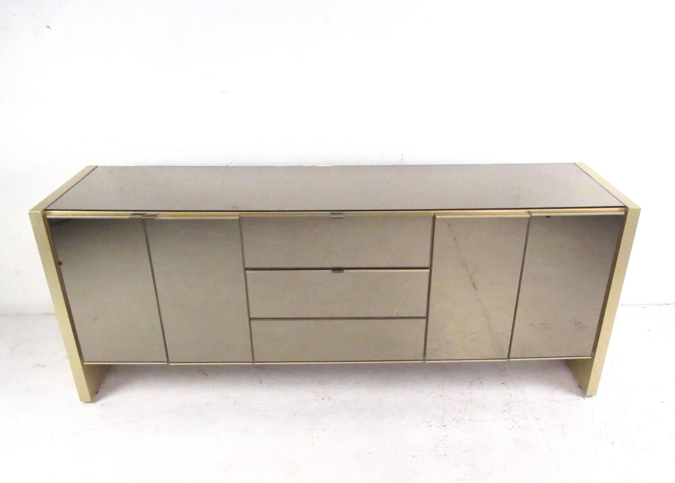 This stunning vintage cabinet makes a stylish storage piece for any interior. Tinted mirror finish is wonderfully complimented by brass trim, while it's clean lines showcase it's mid-mod charm. Please confirm item location (NY or NJ).