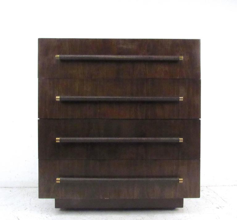 This unique designer dresser by Robsjohn-Gibbings for Widdicomb features four drawer storage in a wonderful natural finish. The rich dark tone of the wood contrasts nicely with the brass trim, while wicker covered pulls add further to it's unique