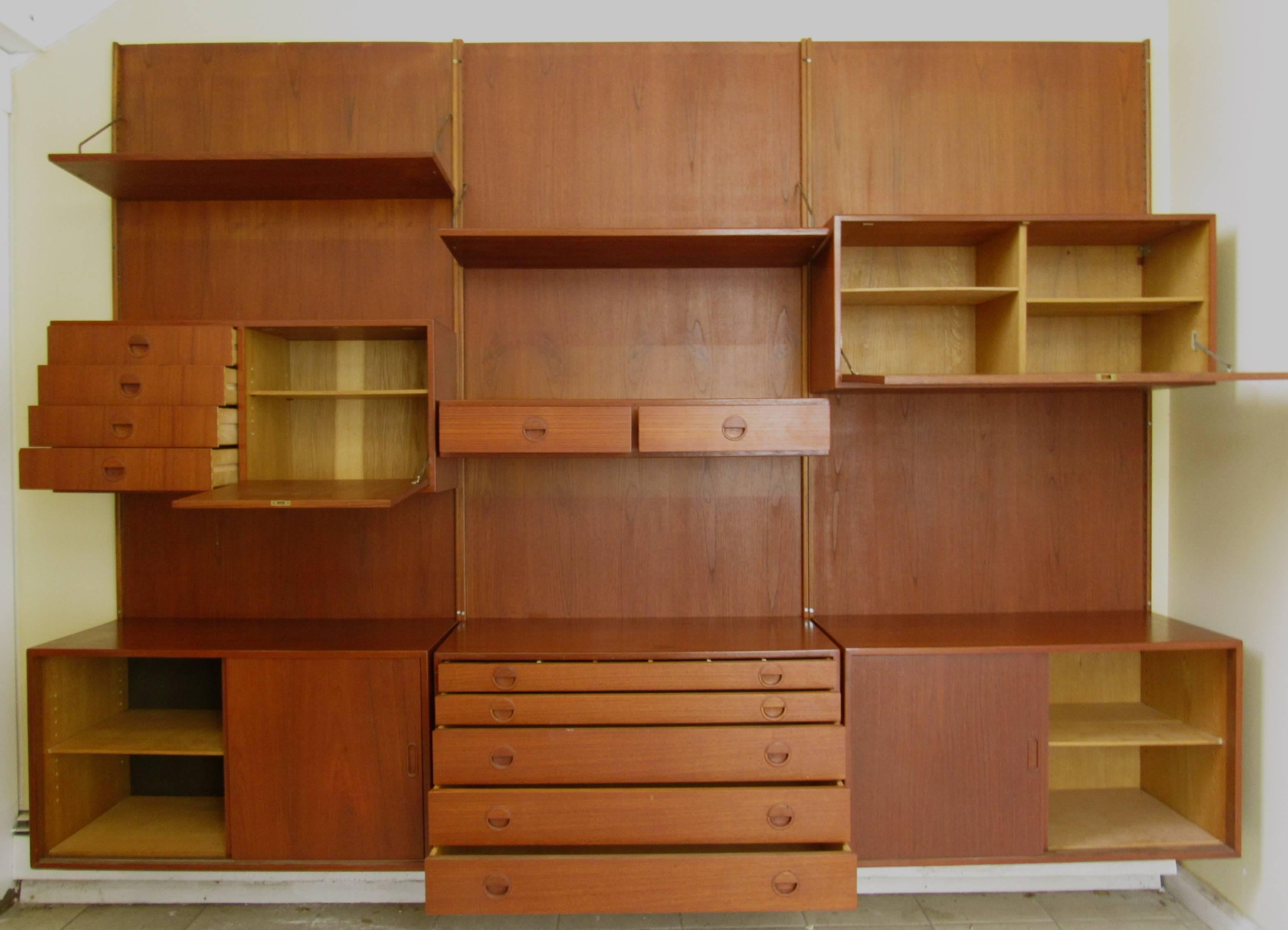 This vintage teak wall unit features three-panel backsplash with modular cabinets whose arrangement can be customized. Ideal wall shelving for dining room or shop display, features storage and shelf space perfect for Mid-Century interiors. Please