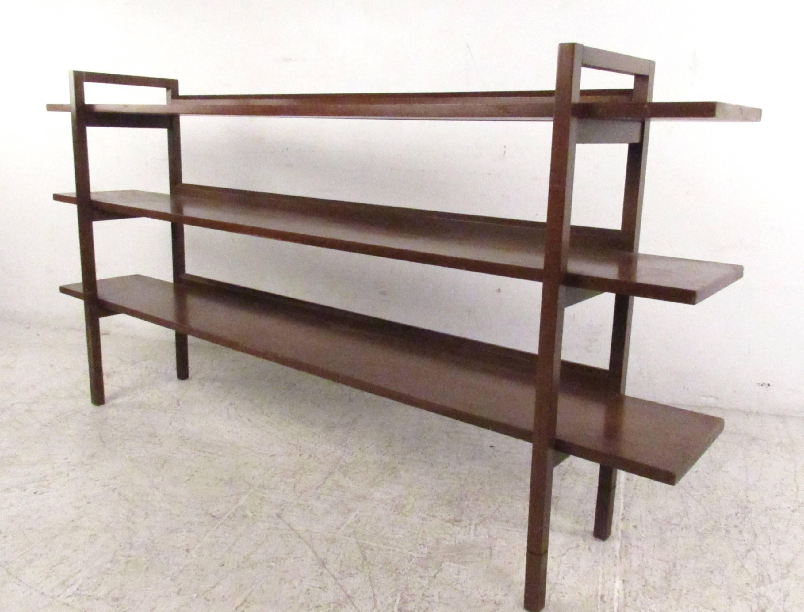 This unique Mid-Century bookshelf features three open back walnut shelves with a slight raised edge on the back. Minimalistic Mid-Century style make this a unique shelf perfect for books, kitsch, or shop display. Please confirm item location (NY or
