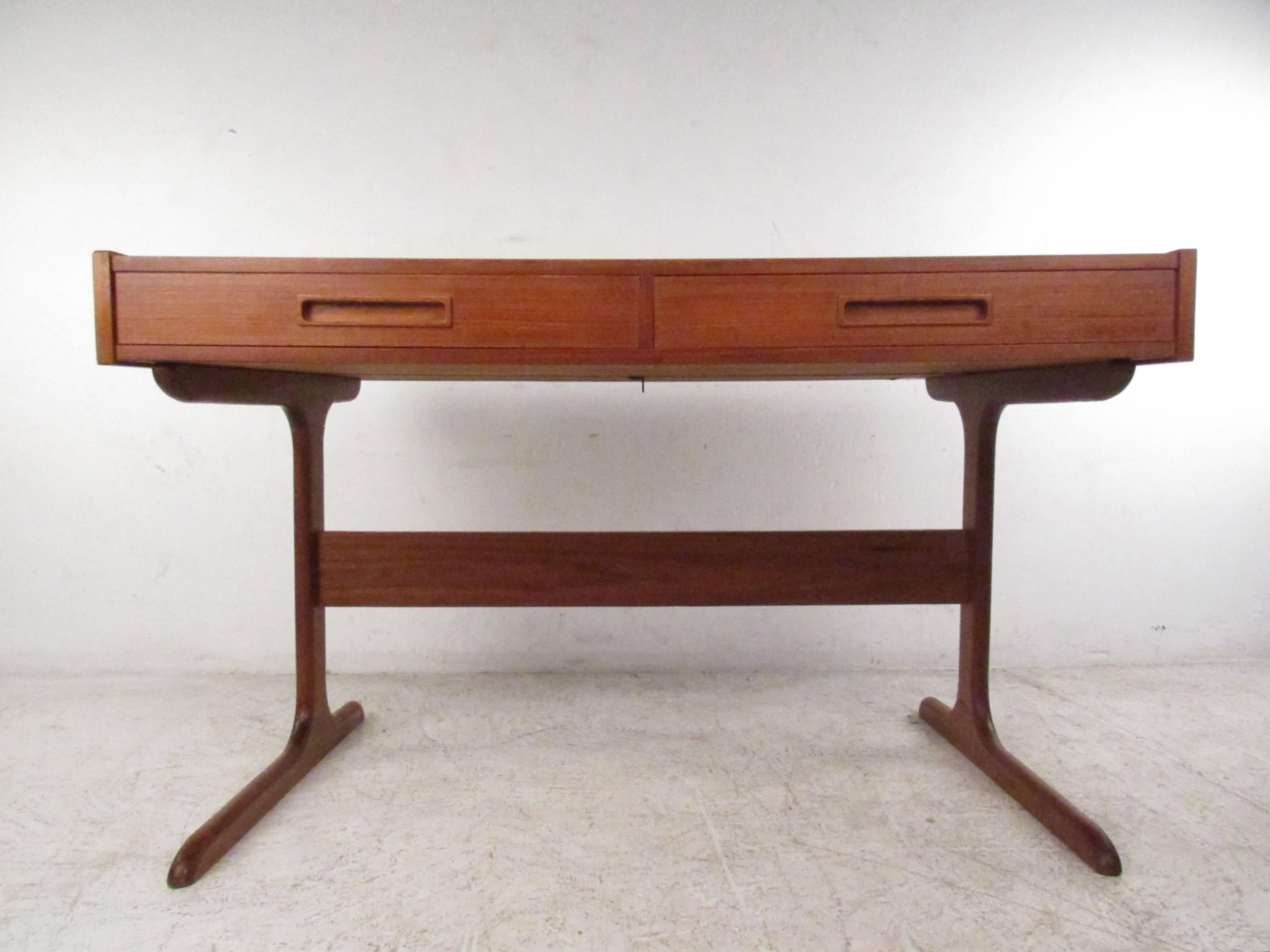 This stylish Mid-Century desk features vintage teak finish, two-drawer storage and a unique hidden organizational cubby. Sculpted sled legs feature a stretcher for added support, while the finished teak back makes this a suitable desk or writing