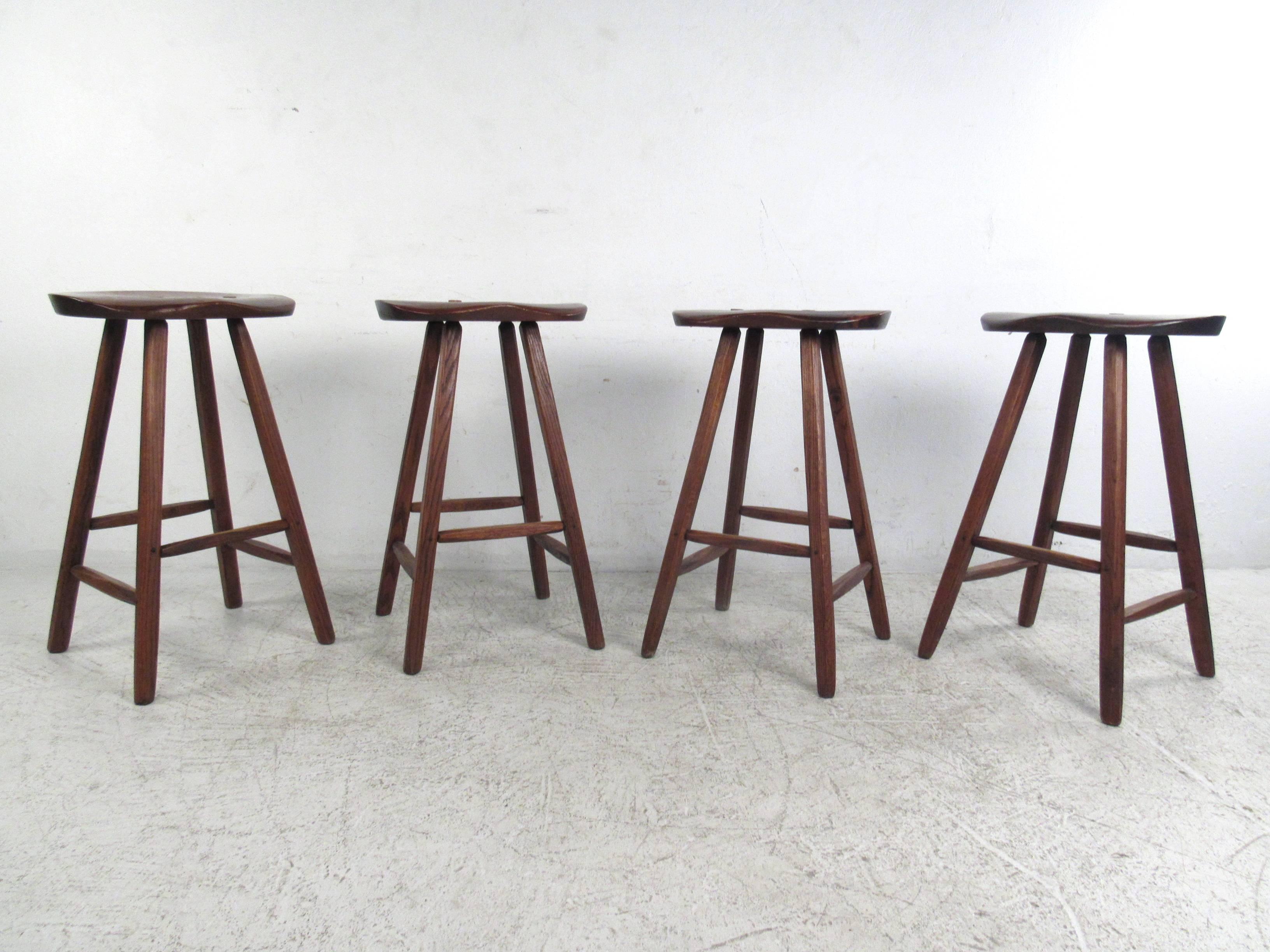 This set of four vintage stools measure just under 30 inches high, making them a unique option for counter or bar use. Primitive carved wood style is accented by dovetailed construction and tapered stretchers. The unique shape of the Primitive style