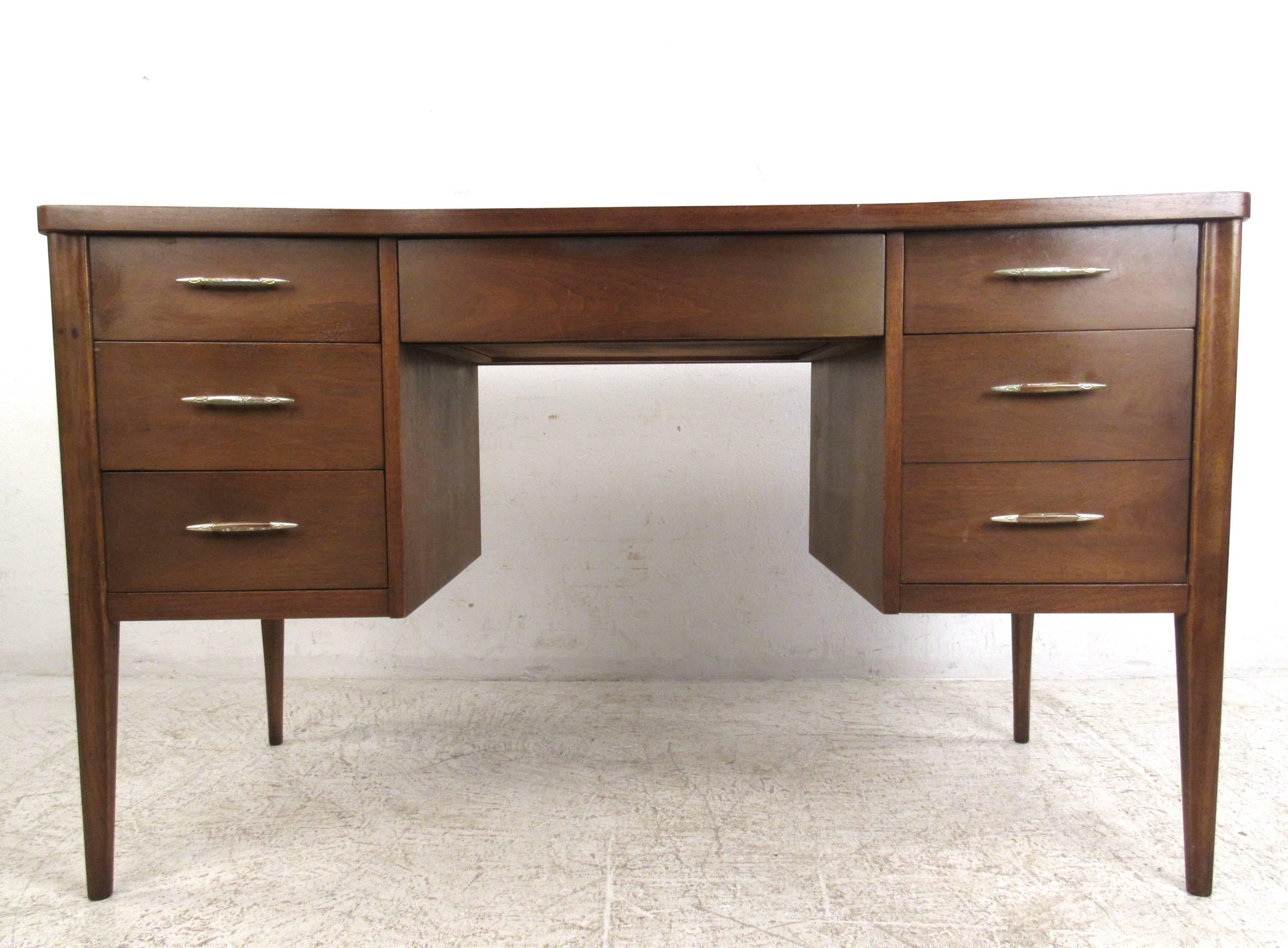 This mid-century walnut dresser features a unique sculpted front design with sturdy walnut legs. Spacious workspace with plenty of drawer space for organization and storage. Unique drawer pulls add to the vintage charm of the piece, please confirm