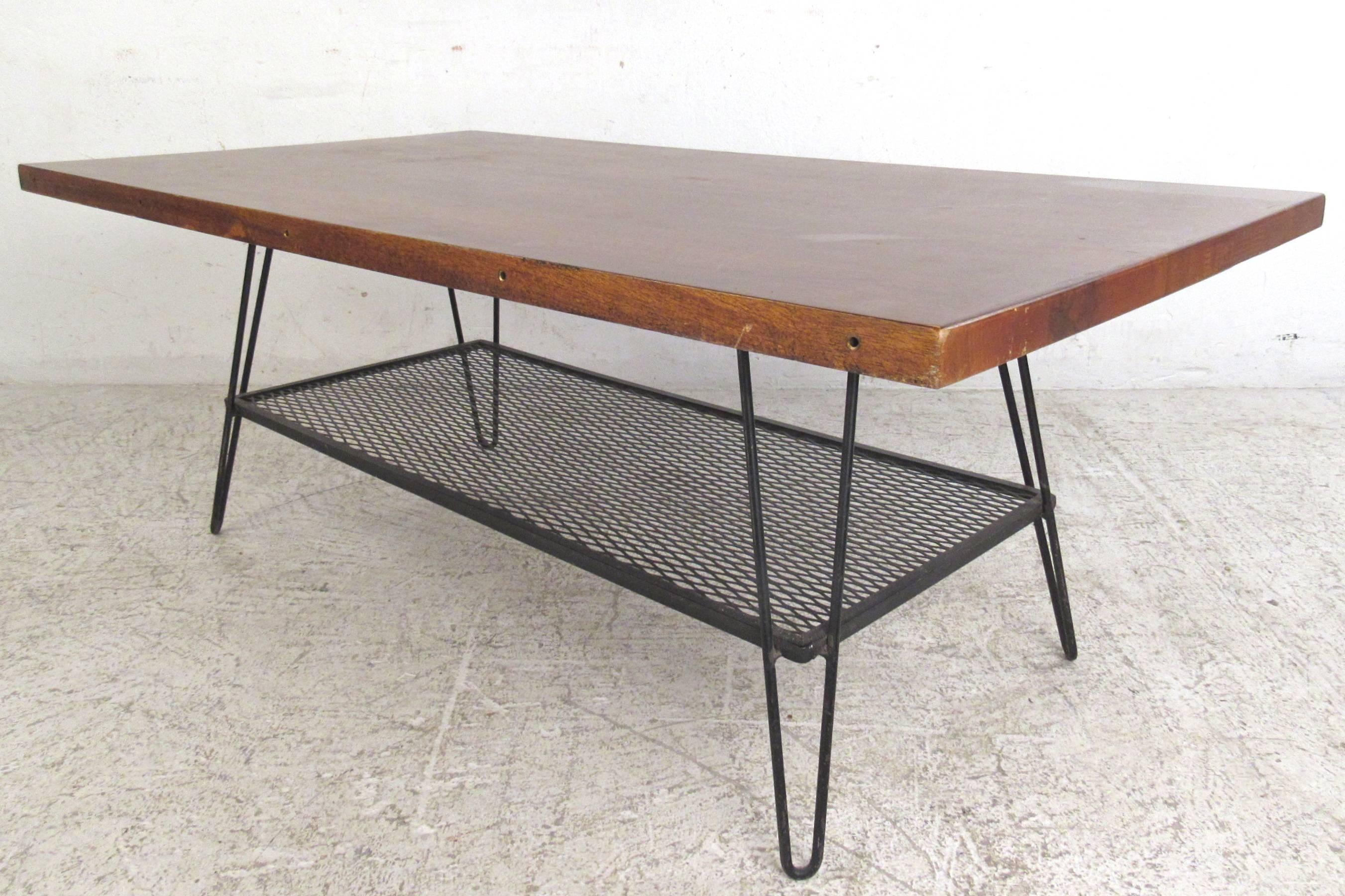 This unique vintage coffee table features a hardwood top with second tier metal shelf. Hairpin legs wonderfully compliment this Industrial style Mid-Century table. Please confirm item location (NY or NJ).