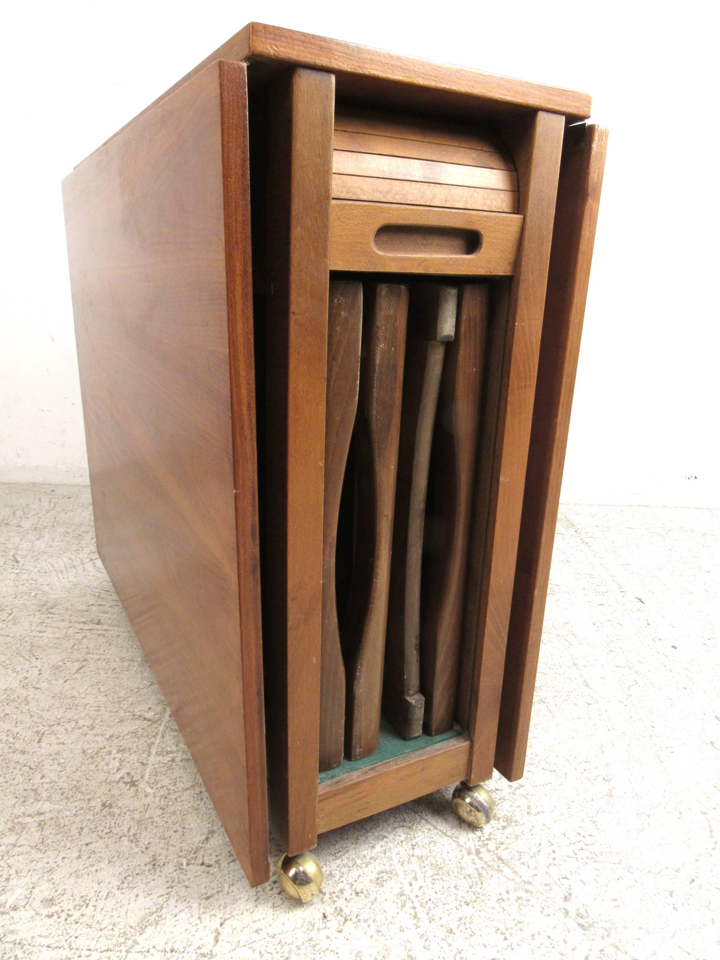 Vintage Danish modern dining set with teak table and four folding chairs. Chairs stow away inside the table. Table is on wheels for easy movement. Either leaf can be set up. Please confirm item location (NY or NJ).