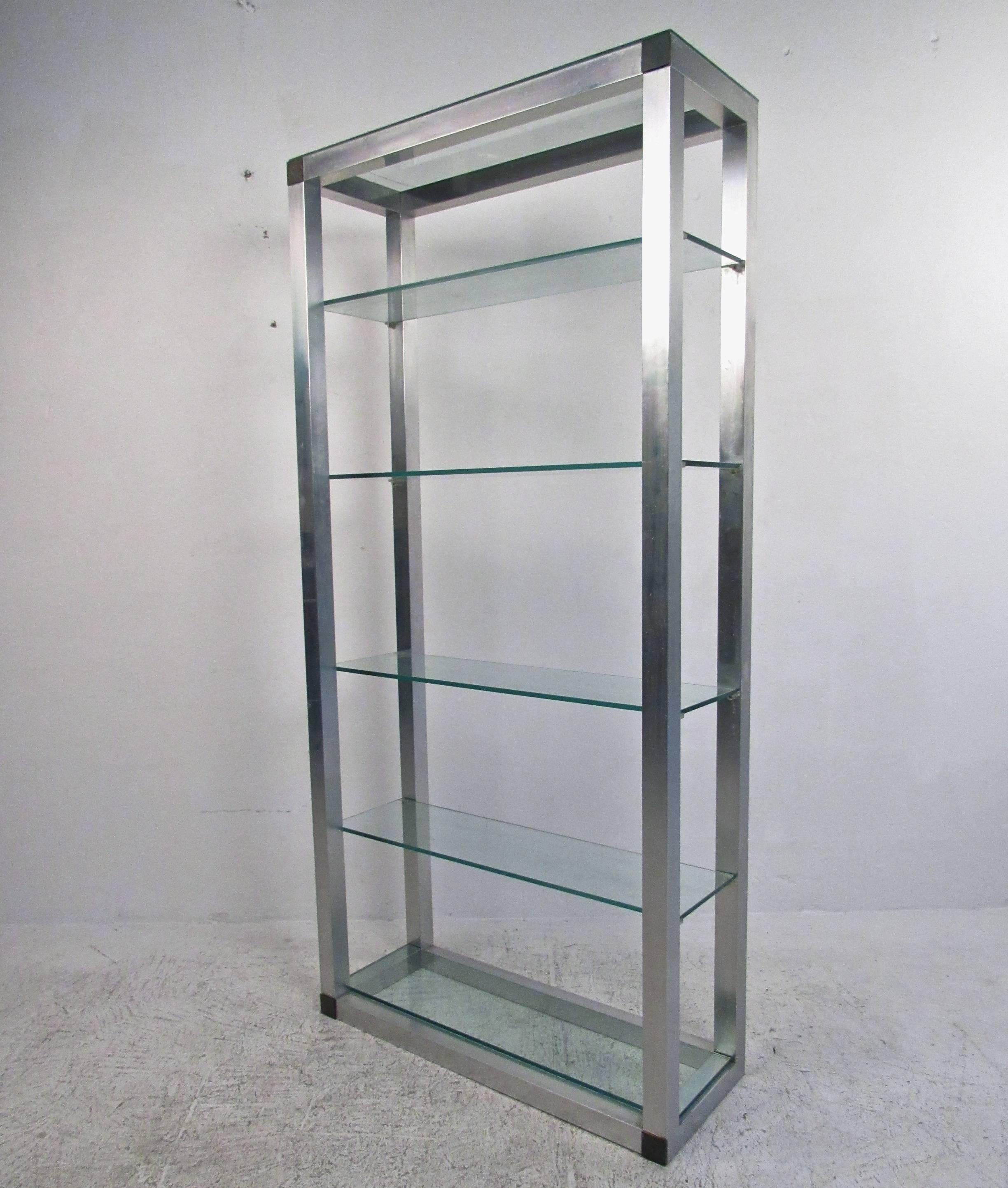 This matching pair of vintage display shelves make an ideal storage shelving system for a variety of interiors. Aluminum finish with corner trim is outfitted with thick glass shelves. Mid-Century Modern style meets plenty of display or storage space
