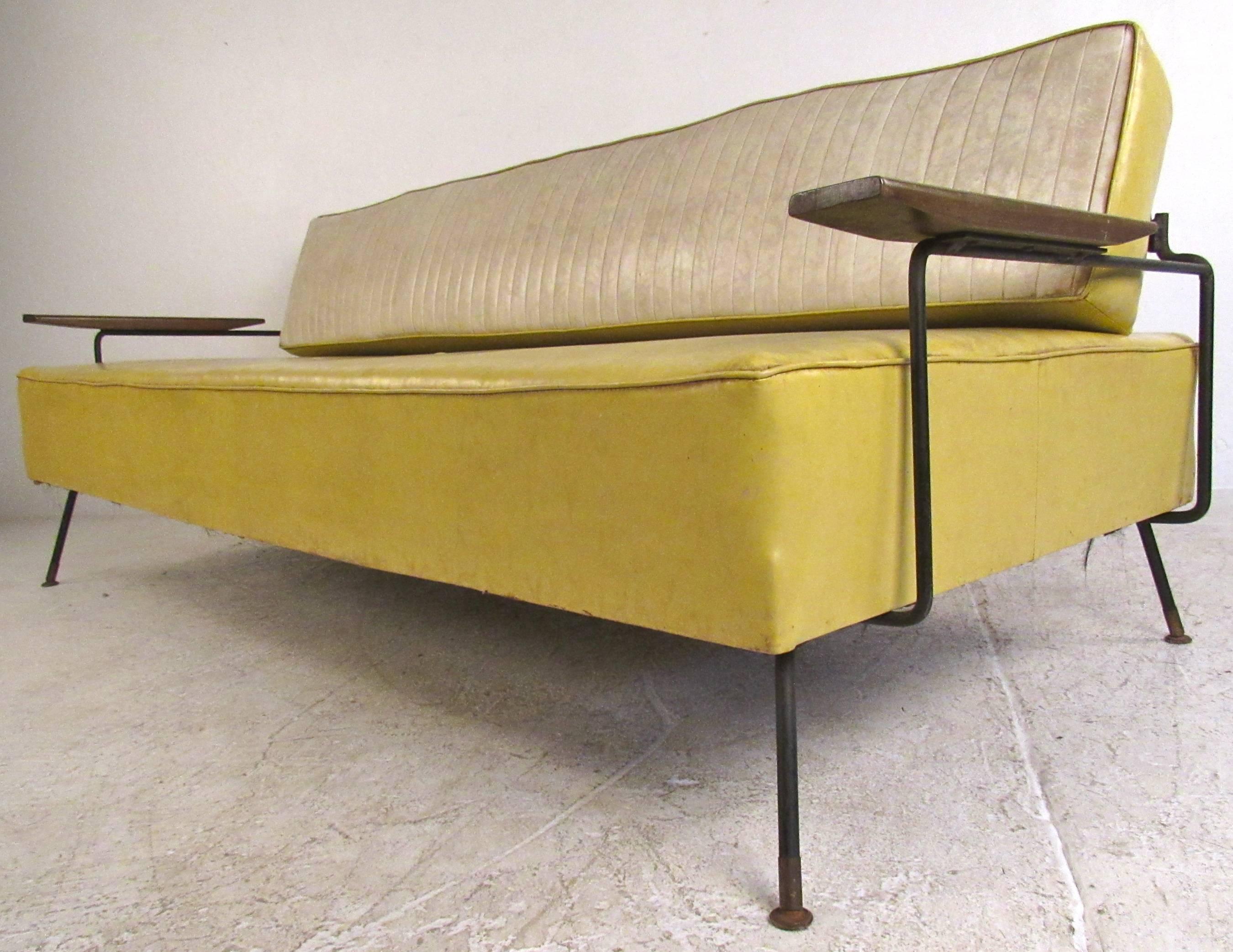 This unique vintage daybed features durable vinyl covering with cast iron frame. Spacious seating area expands even further with hinged seat back. Wooden armrests and fluted vinyl add to the midcentury charm of the sofa. Manufactured by Selrite,
