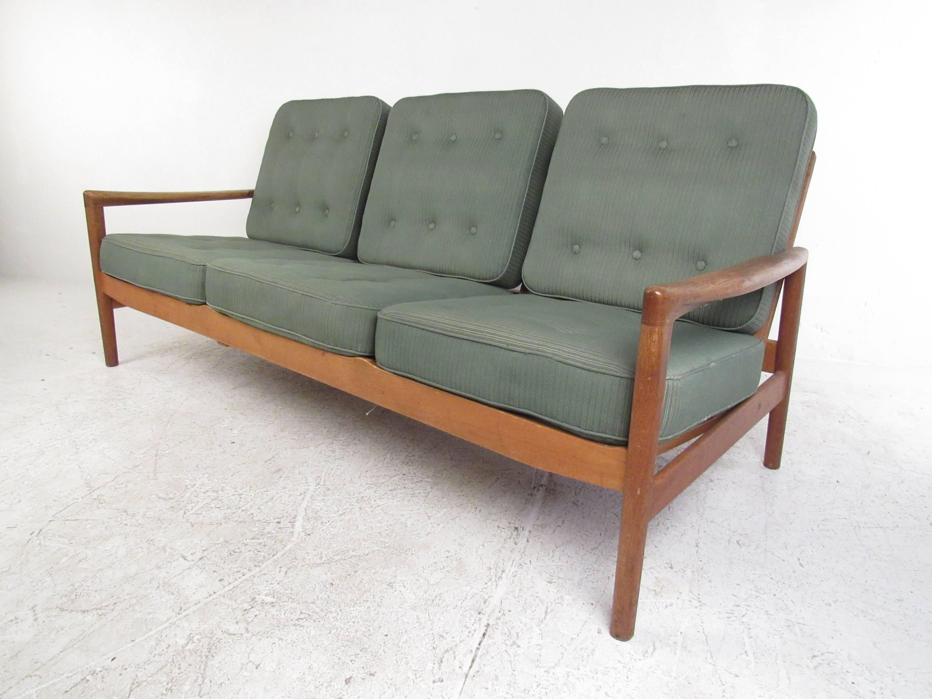 This vintage three-seat sofa features a unique sculpted arm frame with tufted cushions. Mid-Century Modern style meets timeless comfort with this versatile sofa, perfect for home or business. Please confirm item location (NY or NJ).