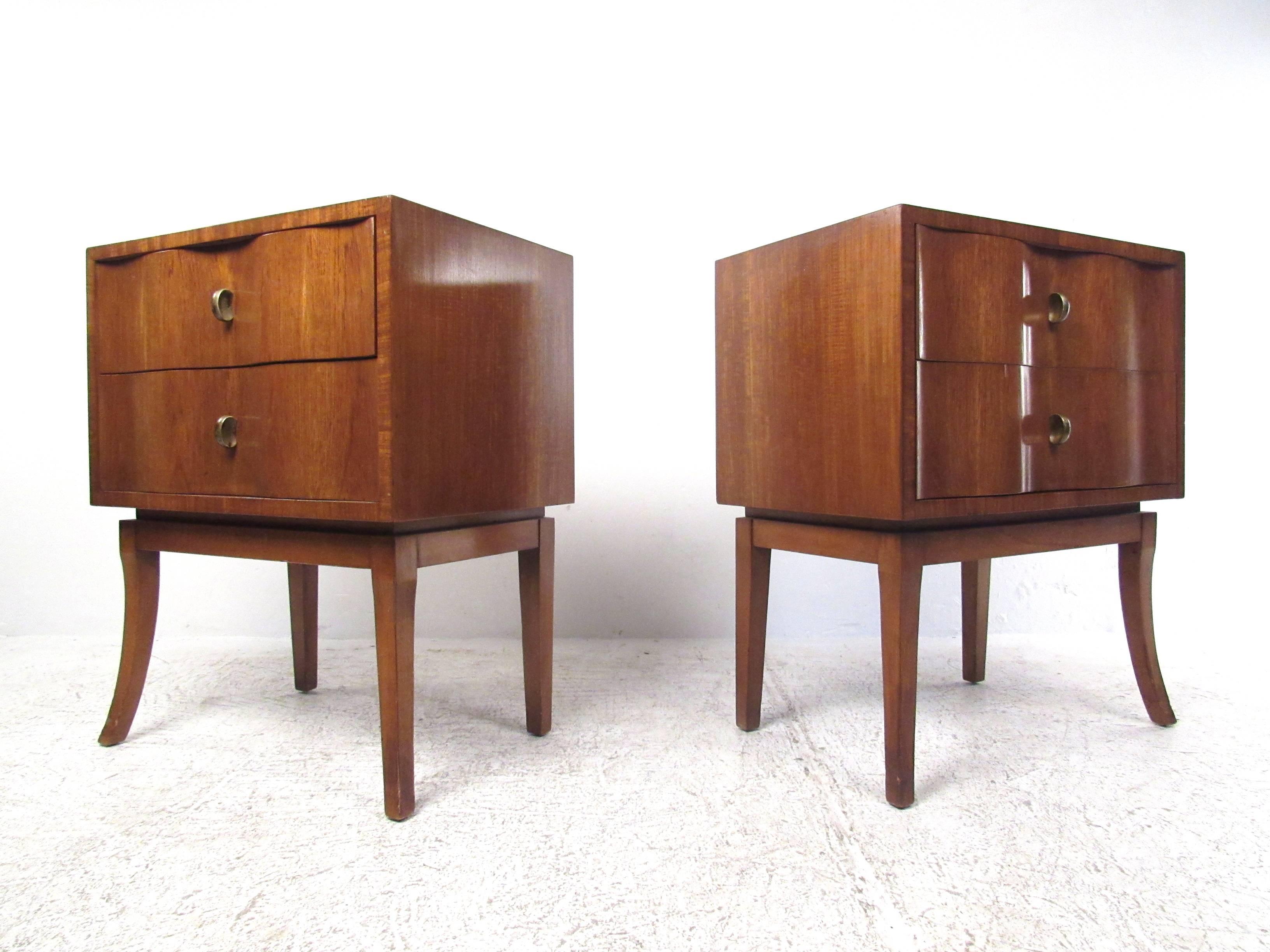 The unique sculptural design of this matching Mid-Century pair features uniquely sculpted drawer fronts, extra tall angles legs, and unique brass pulls. Wonderful pair of nightstands, or an exquisite set of occasional Art Deco style side tables for