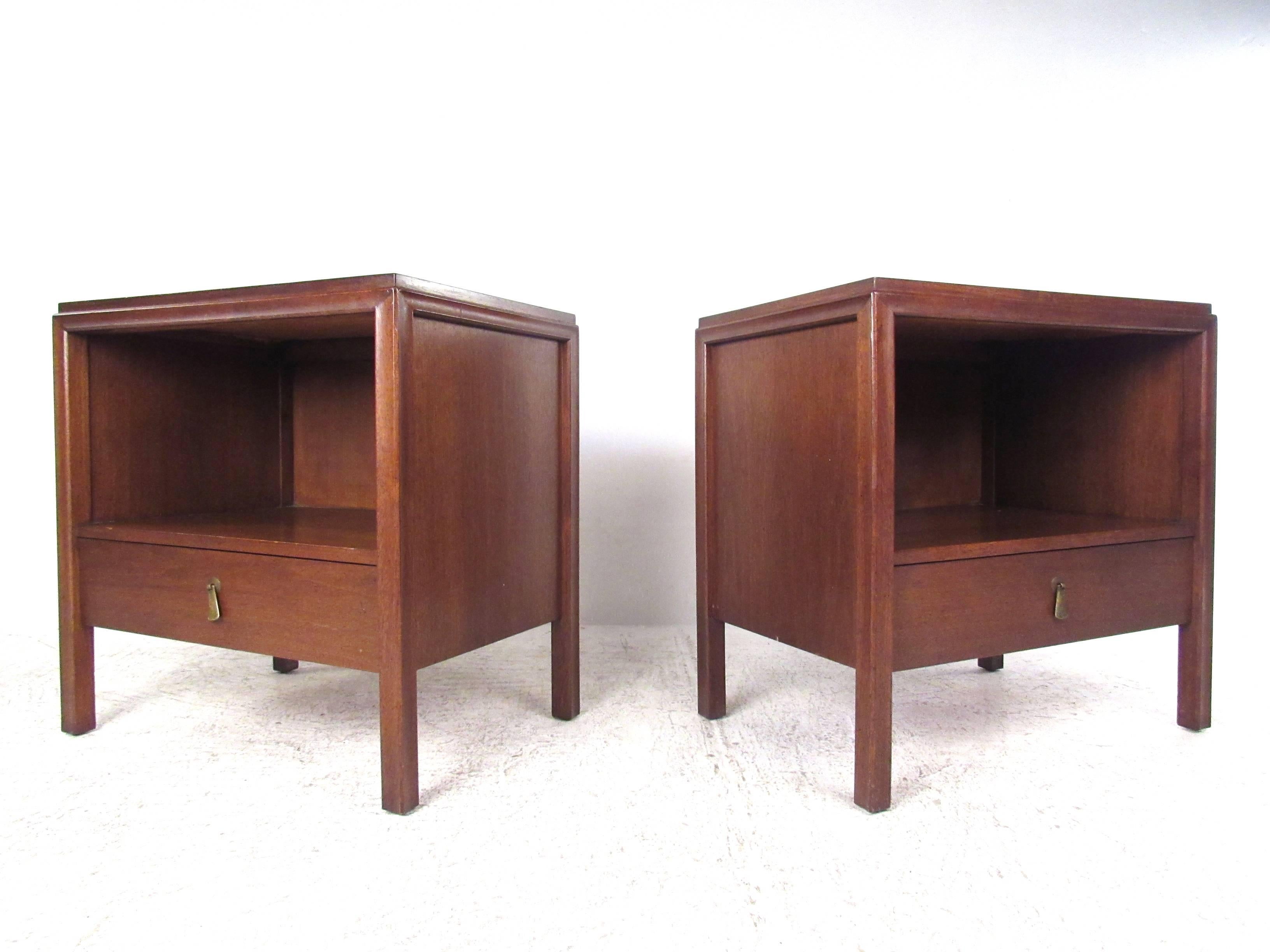 This vintage pair of bedside tables features the Classic Mid-Century style of John Stuart, and offer plenty of convenient storage with spacious cabinet and additional drawer. Unusual hanging brass pulls, a finished back, and a rich vintage walnut